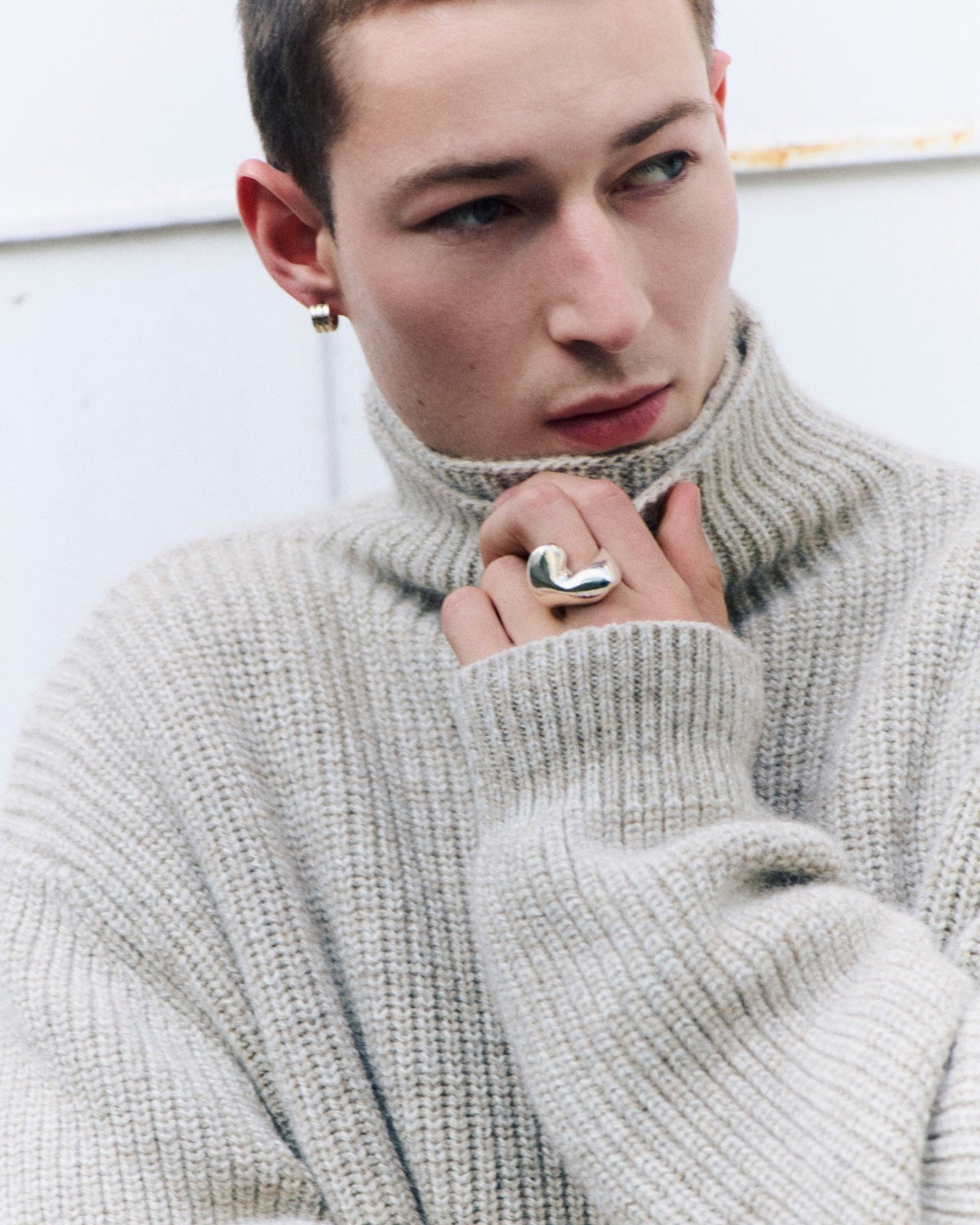 Model wearing AGMES .925 sterling silver mini triple ridge hoops and sculptural Simone Bodmer Turner ring with grey turtleneck sweater.