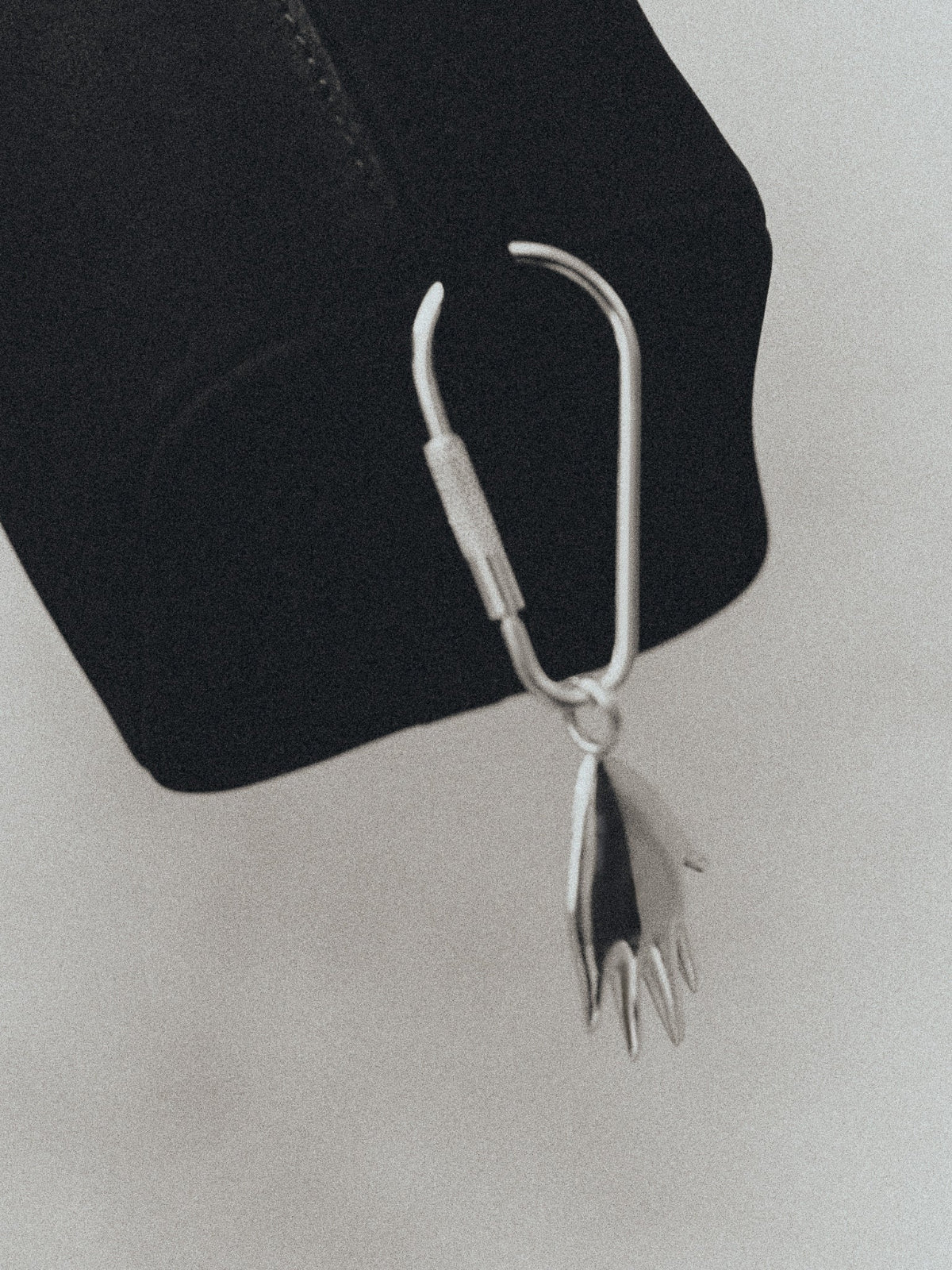 AGMES .925 sterling silver hand shaped Dali Keychain on black suede handbag.