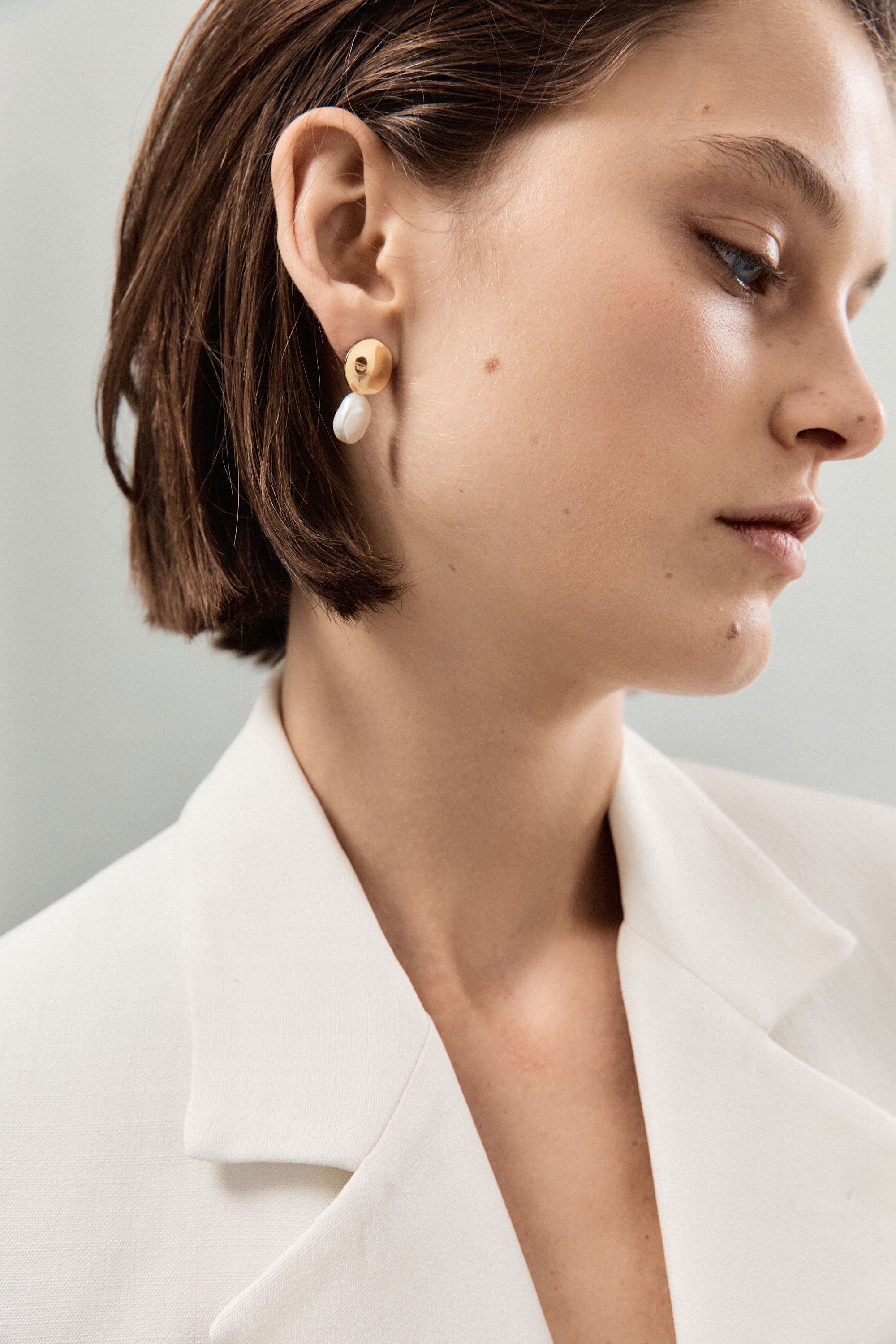 Woman wearing AGMES 18k gold vermeil small round earrings with freshwater pearl drop.
