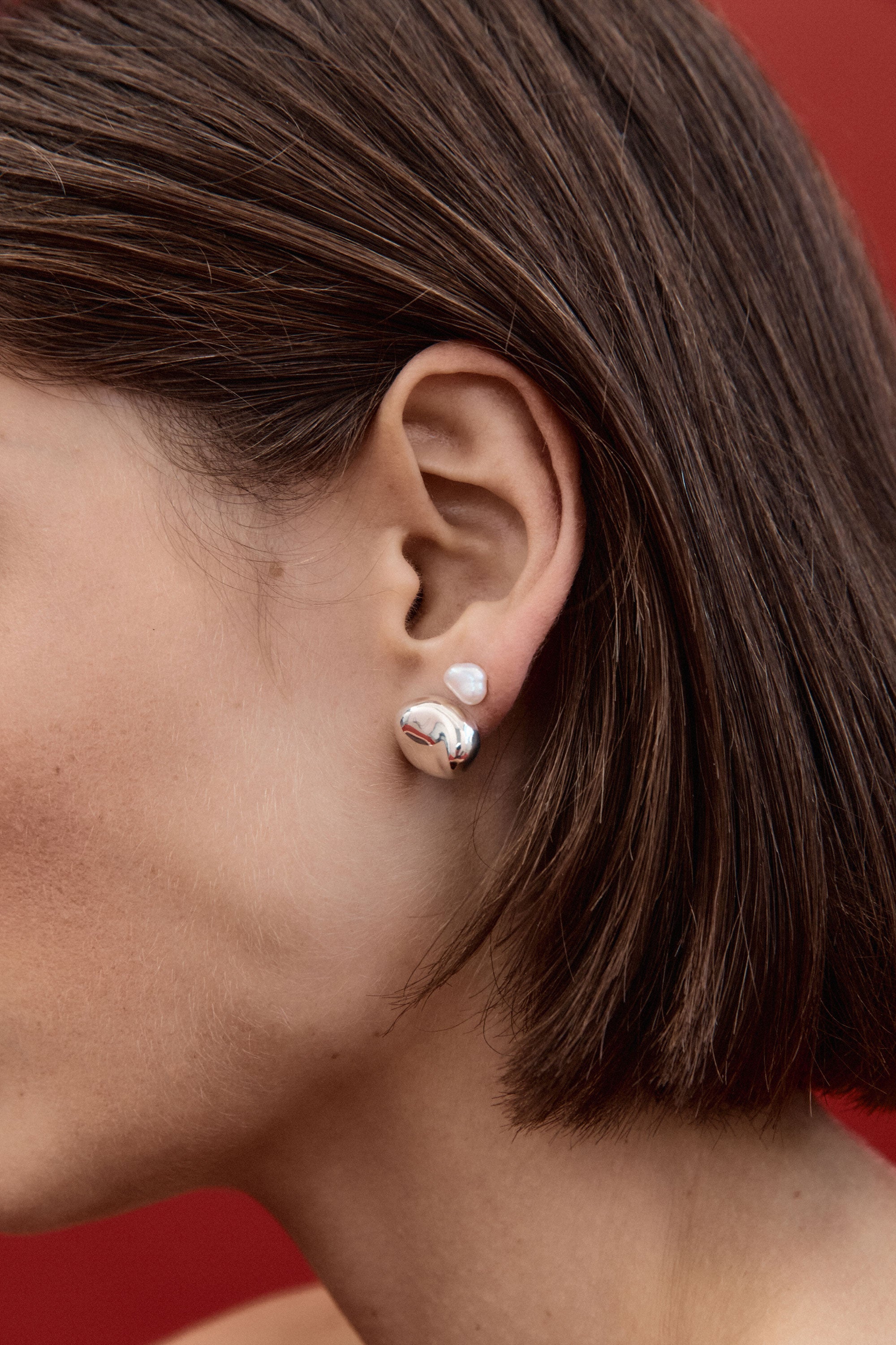 Woman wearing AGMES 0.925 sterling silver sculpted round stud earrings.
