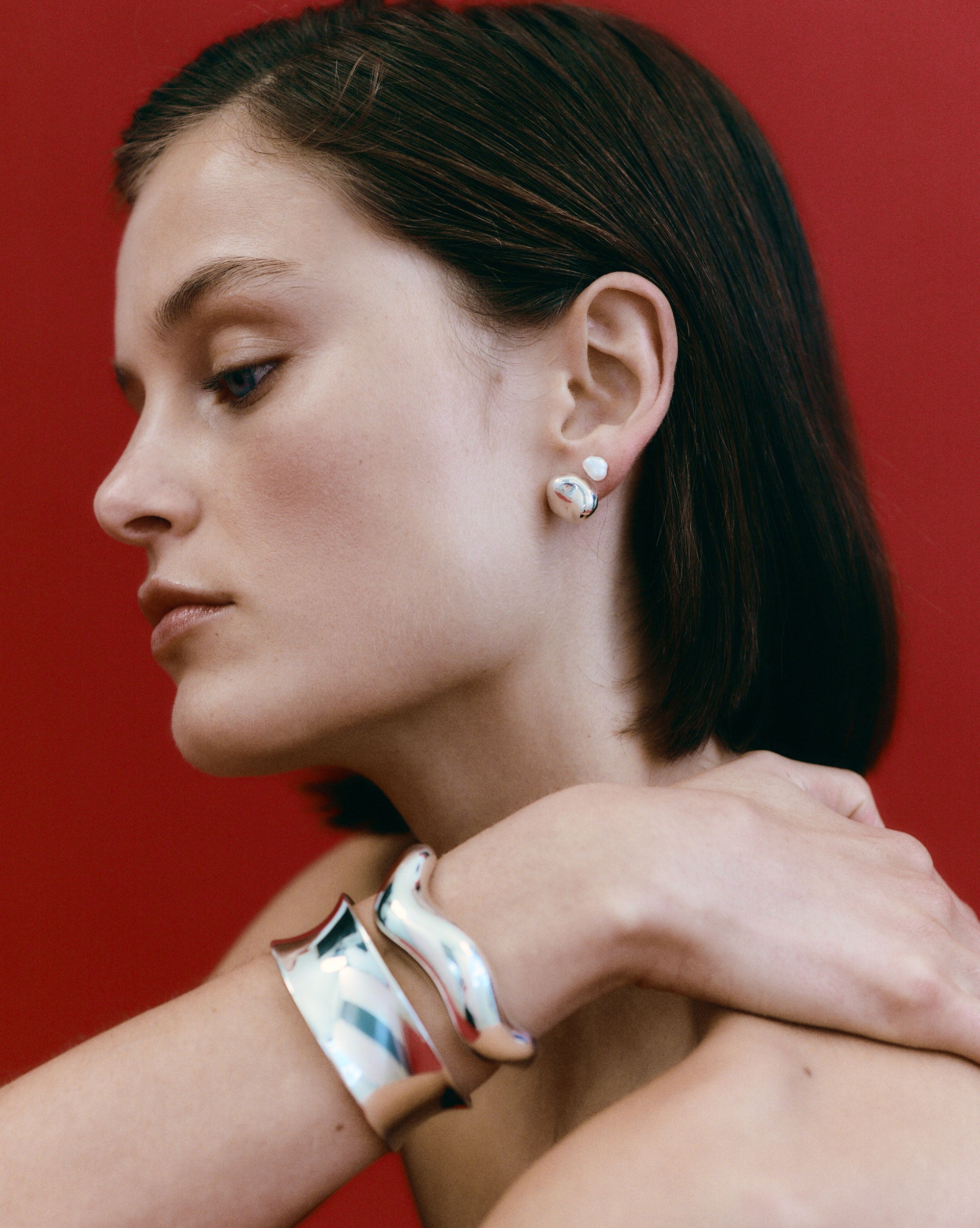 Woman wearing AGMES 0.925 sterling silver sculpted abstract cuff set.