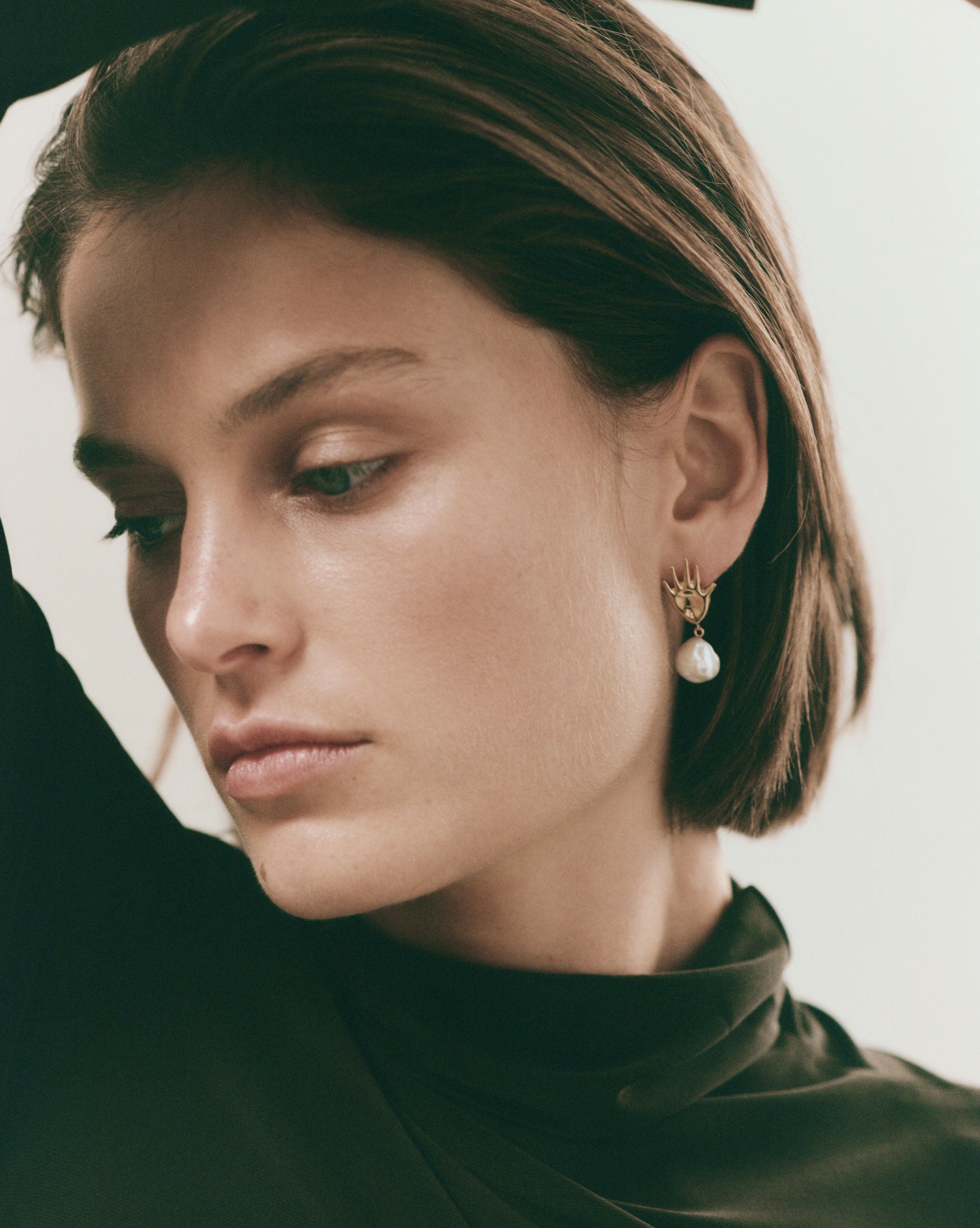 Woman wearing AGMES 0.925 sterling silver abstract hand earrings with baroque freshwater pearl drop.
