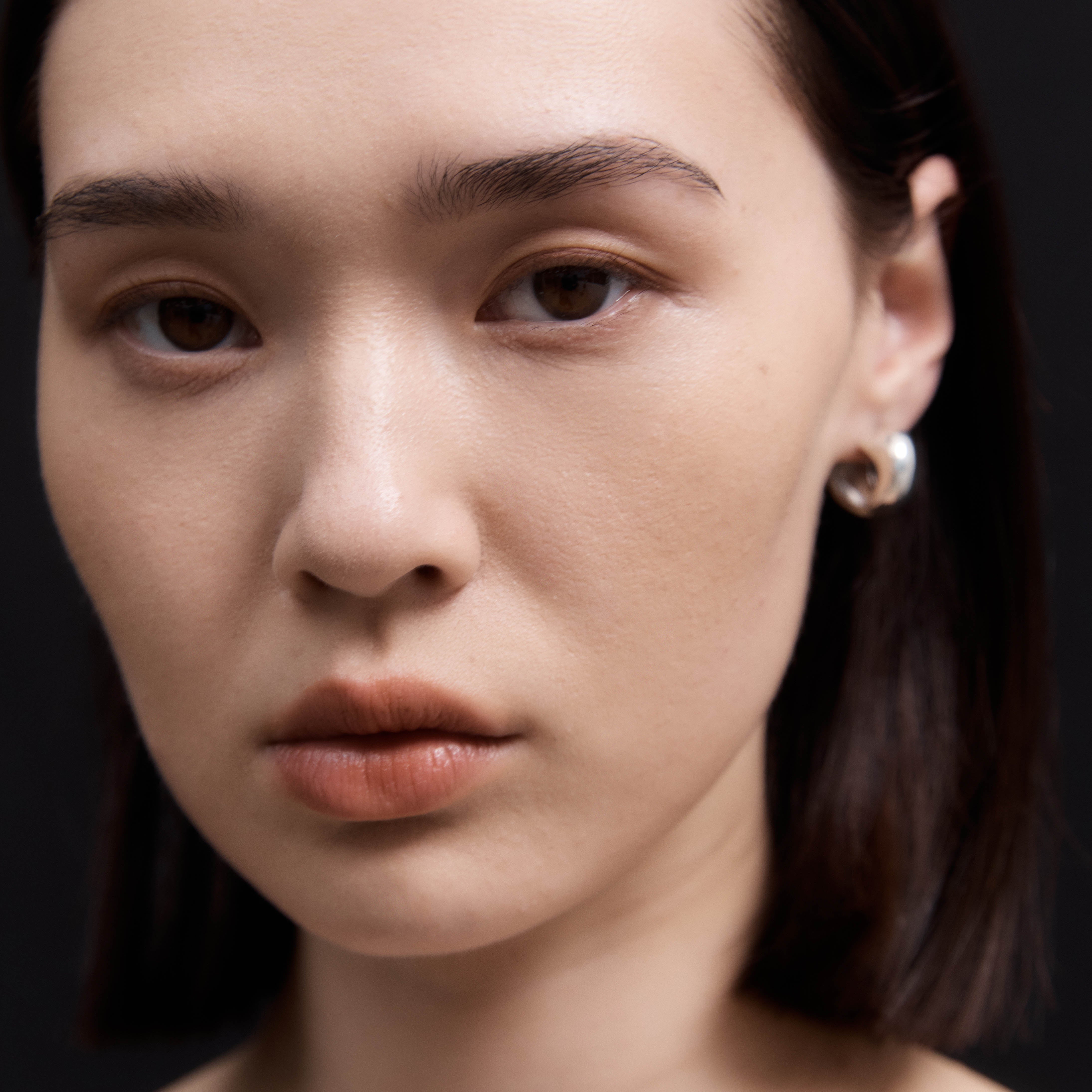 Woman wearing AGMES 0.925 sterling silver small hoop earrings.