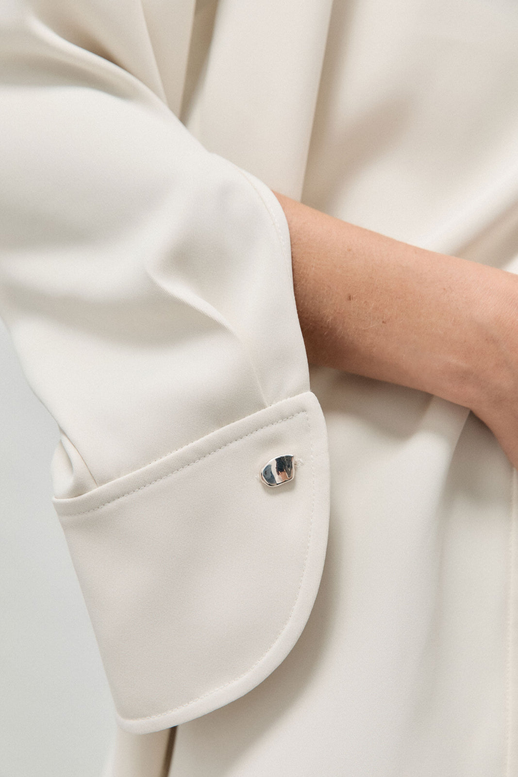 Model wearing AGMES .925 sterling silver sculptural heart Sum of Parts cufflink on white shirt.