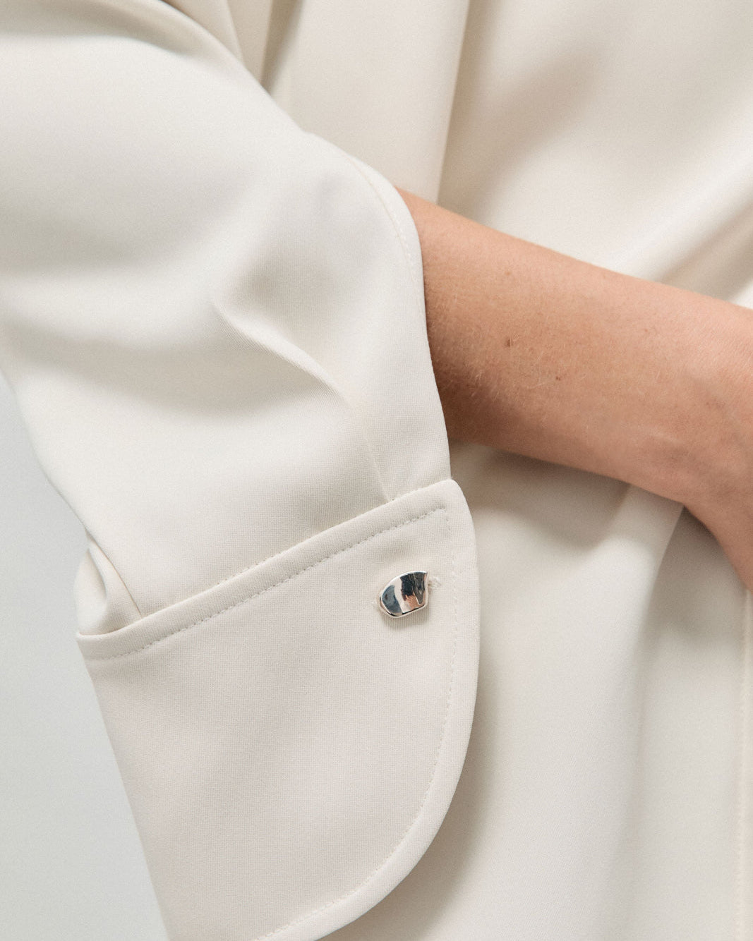 Model wearing AGMES .925 sterling silver sculptural heart Sum of Parts cufflink on white shirt.