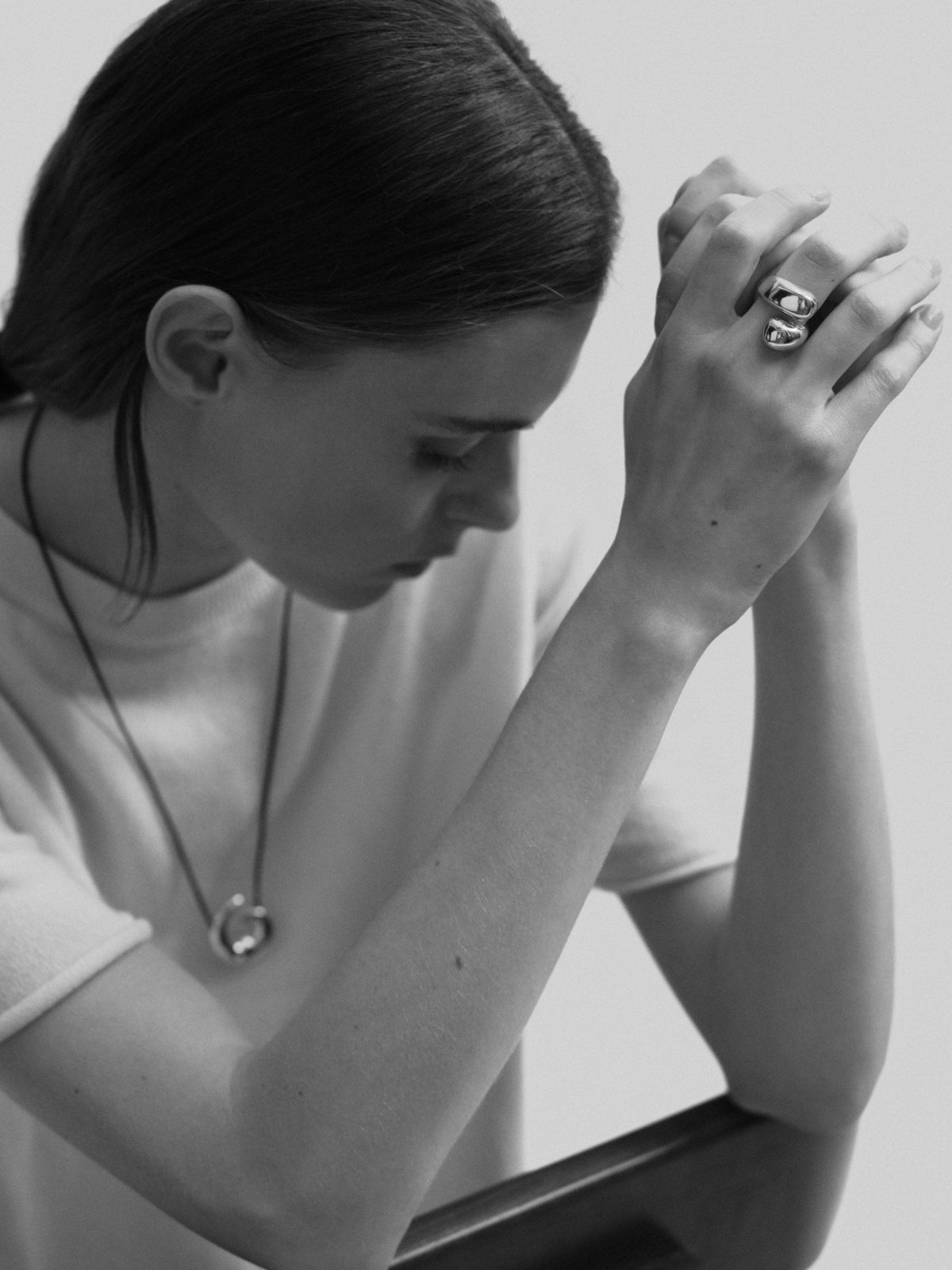 Model wearing AGMES .925 sterling silver sculptural heart spiral Nadia Pendant Necklace and Synergy wrap ring.