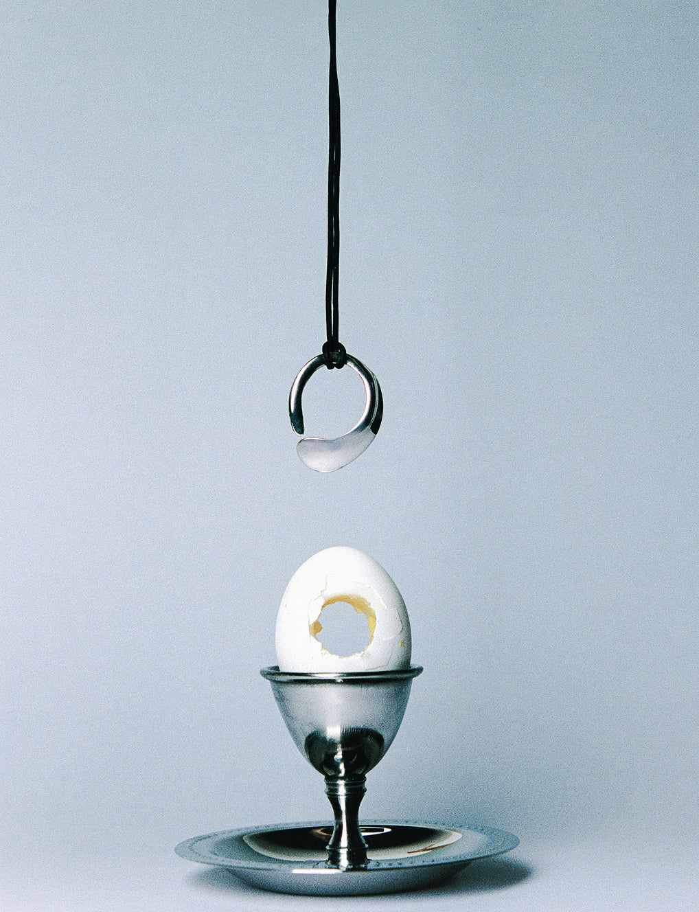 AGMES .925 sterling silver round sculptural open Marta Pedant on black suede cord. Hanging over Egg on silver holder.