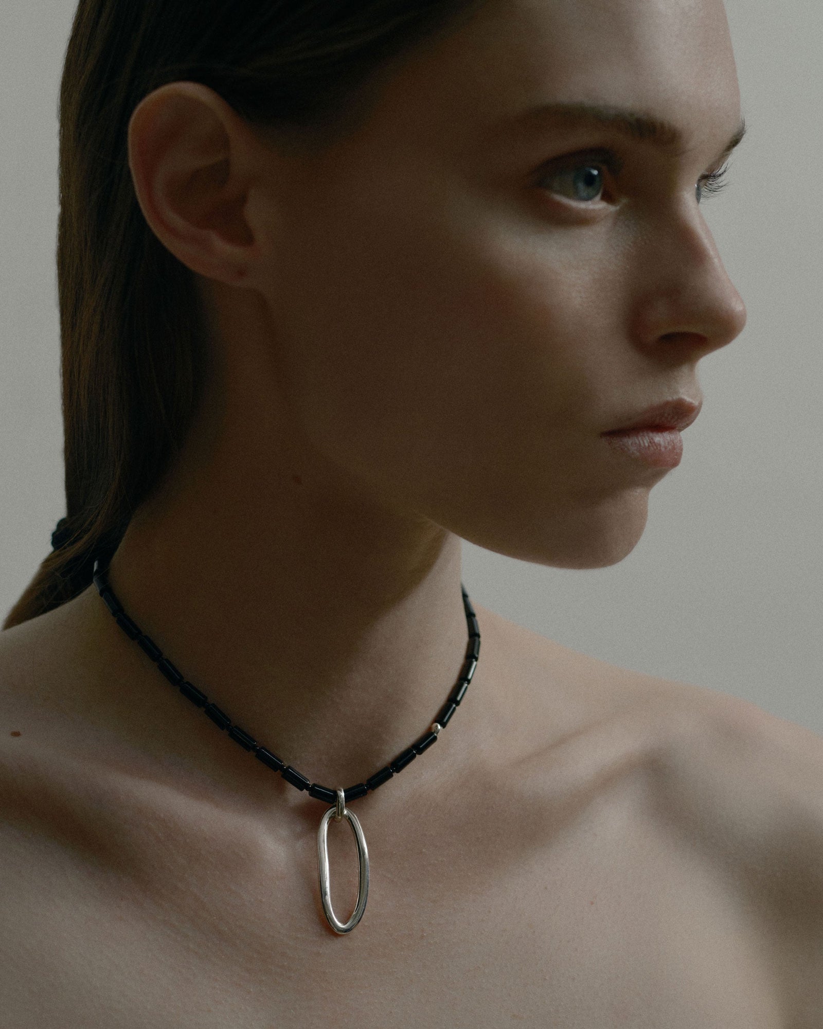 Model wearing AGMES Onyx stone bead necklace with .925 sterling silver pendant and accents
