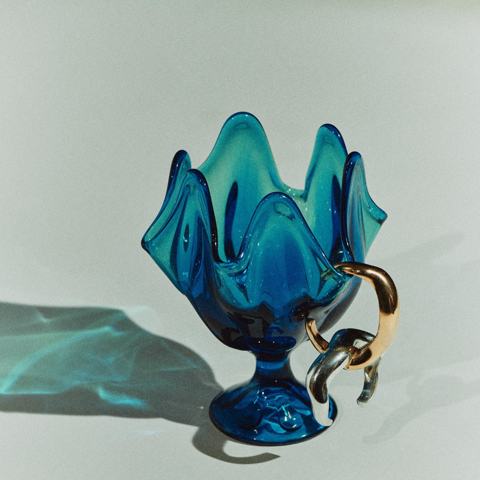 AGMES 0.925 sterling silver and gold vermeil abstract large Astrid cuff set on blue vase on white background.