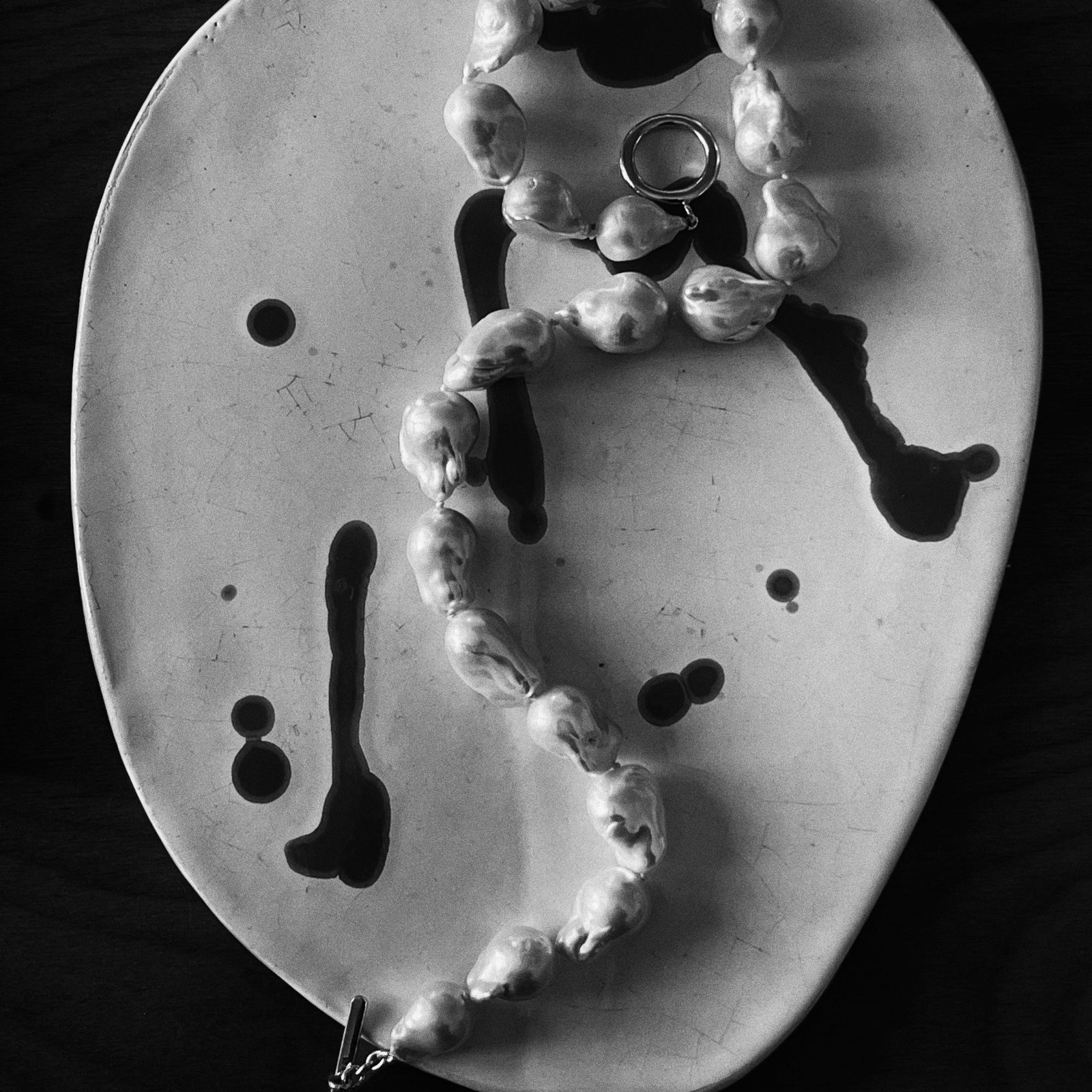 AGMES Baroque freshwater Pearl Necklace on ceramic plate. Black and white image.