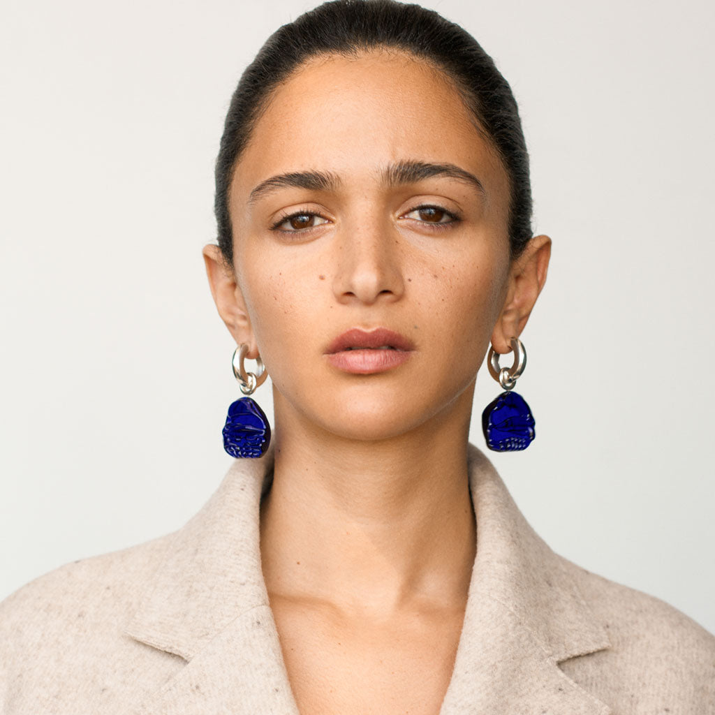 Woman wearing AGMES 0.925 sterling silver hoop earrings with blue Handblown Venetian Glass drop.