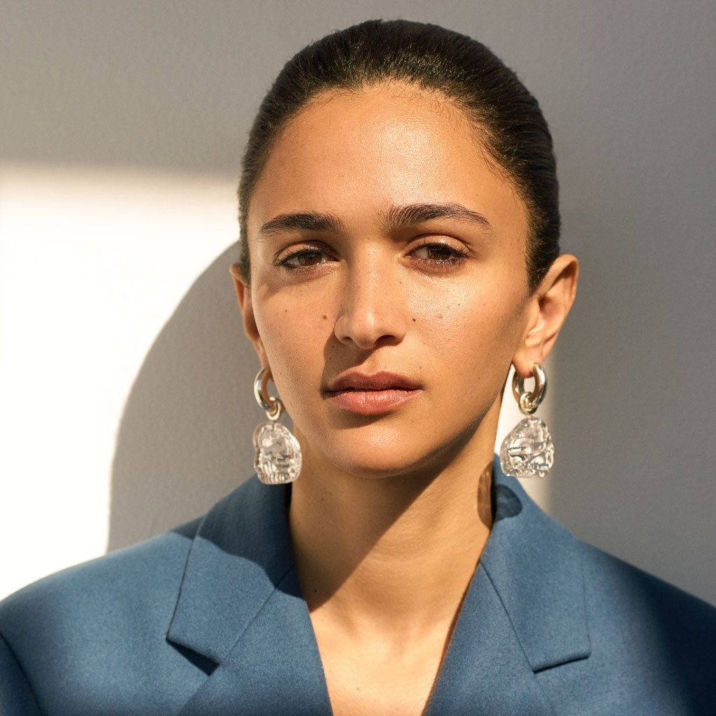 Woman wearing AGMES 0.925 sterling silver hoop earrings with clear Handblown Venetian Glass drop.