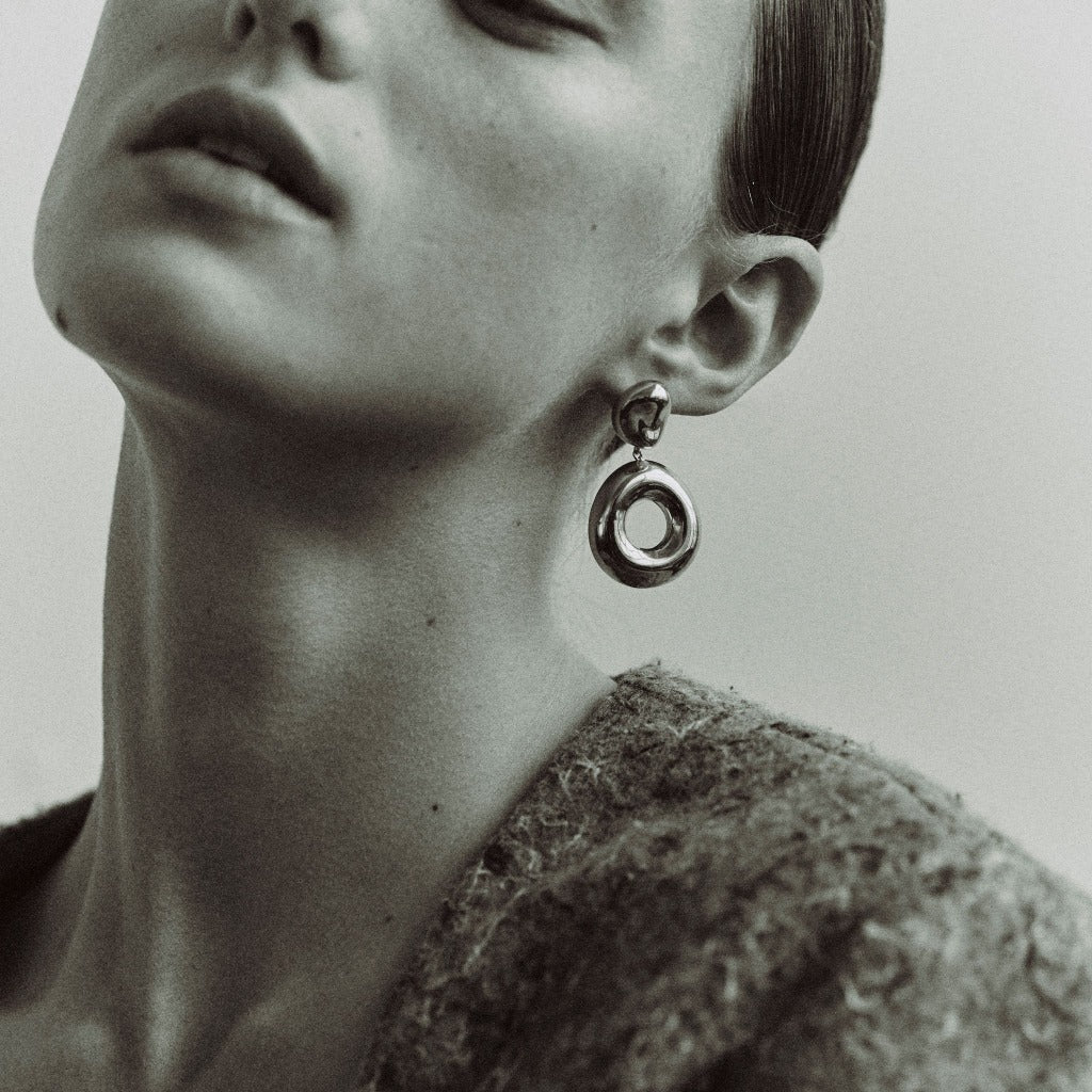 Woman wearing AGMES 0.925 sterling silver earrings with silver drop donut ring.