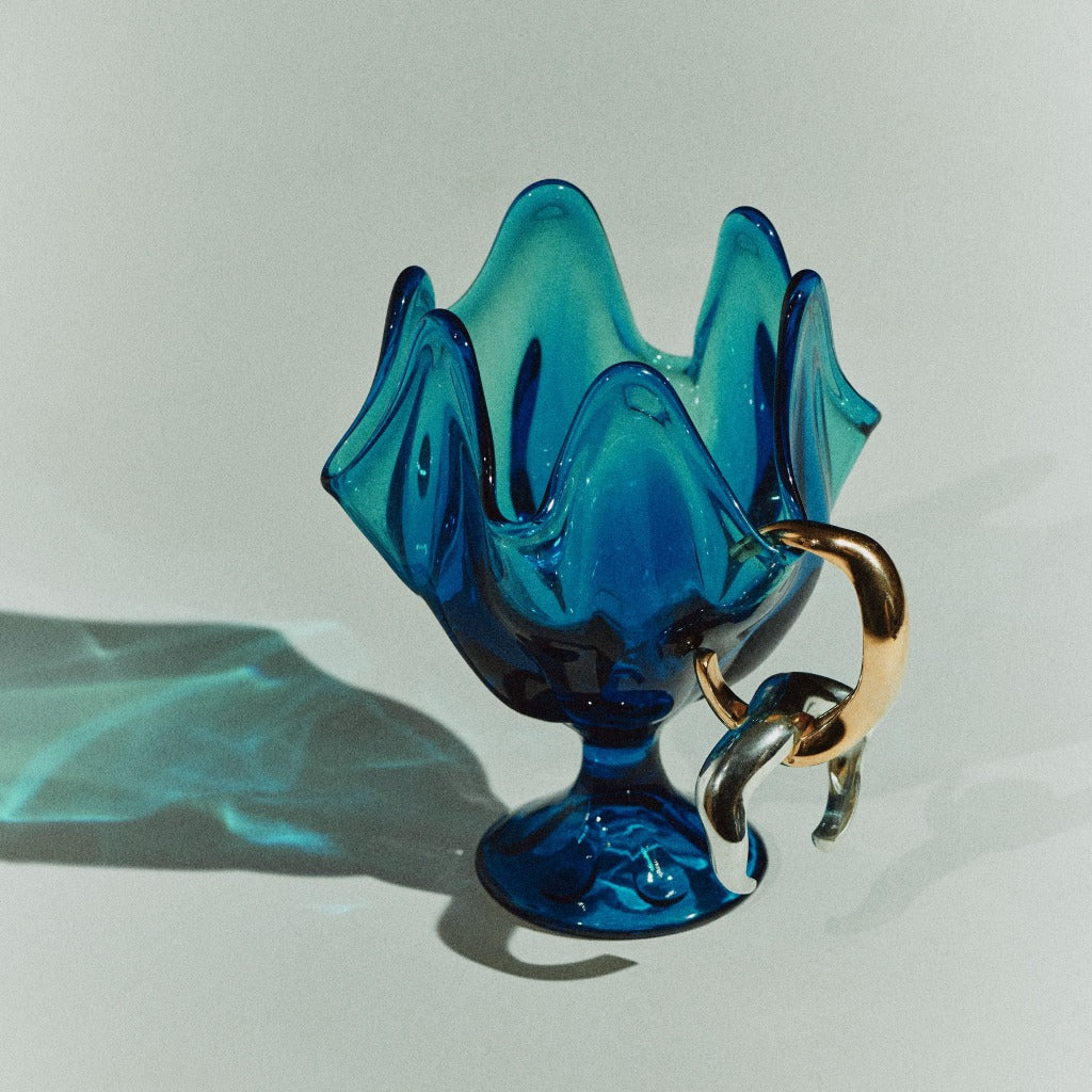 AGMES 0.925 sterling silver and 18k gold vermeil large Astrid sculpted cuff bracelets displayed on blue glass vase.