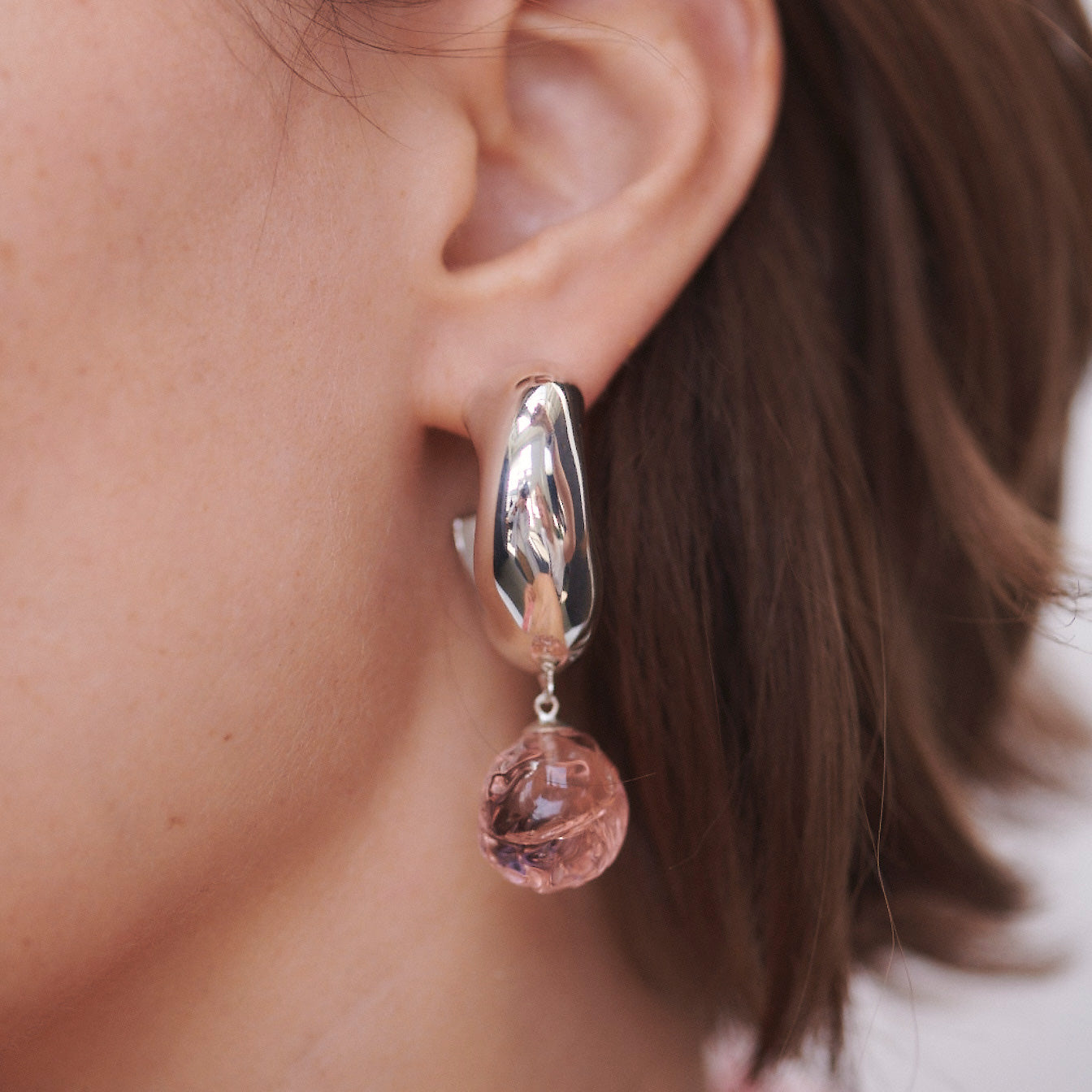 Woman wearing AGMES 0.925 sterling silver medium Cleo hoop earrings with rose glass bead drop.