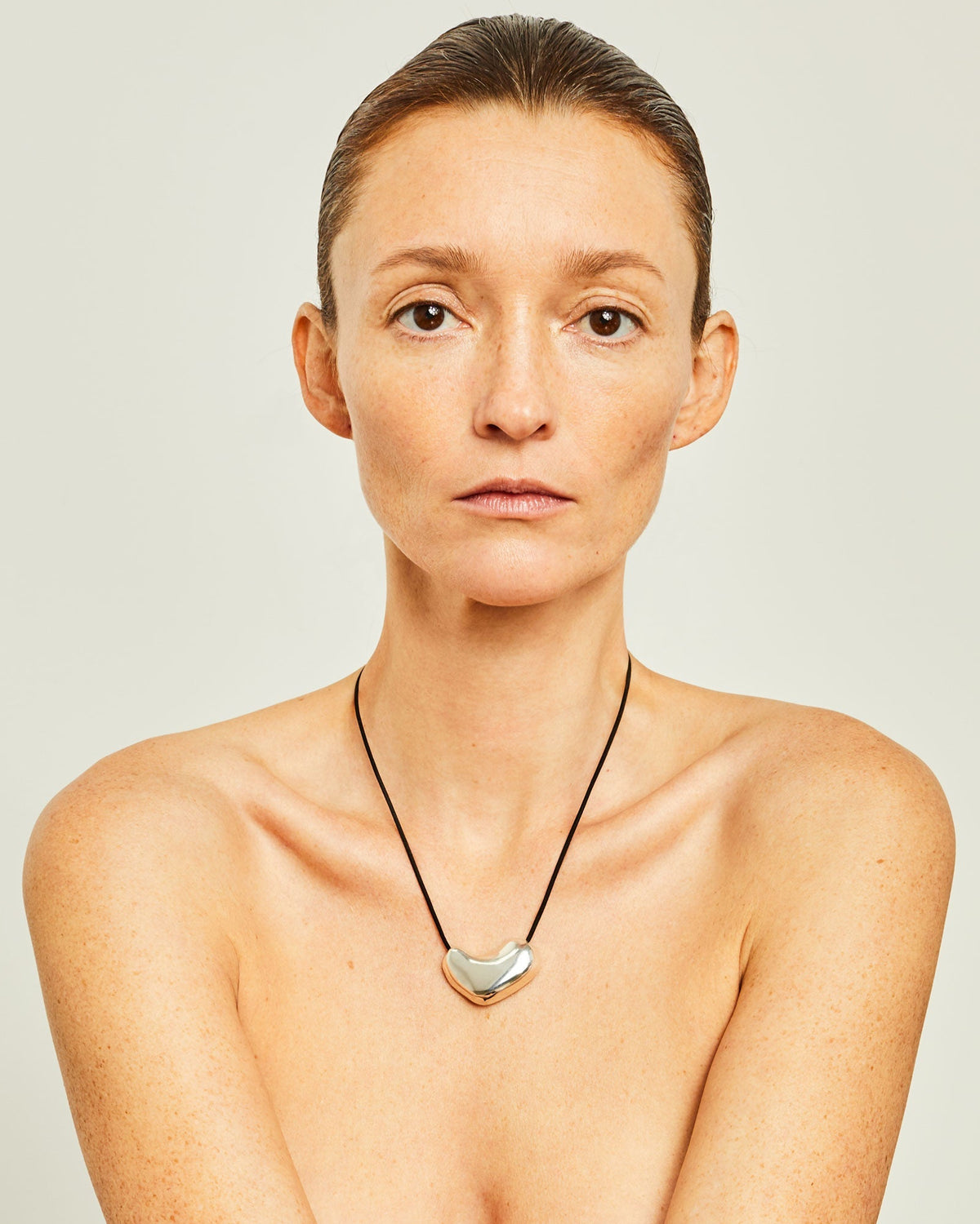 Woman wearing the AGMES .925 Sterling Silver Sculpted Heart Pendant on Black Suede Cord.