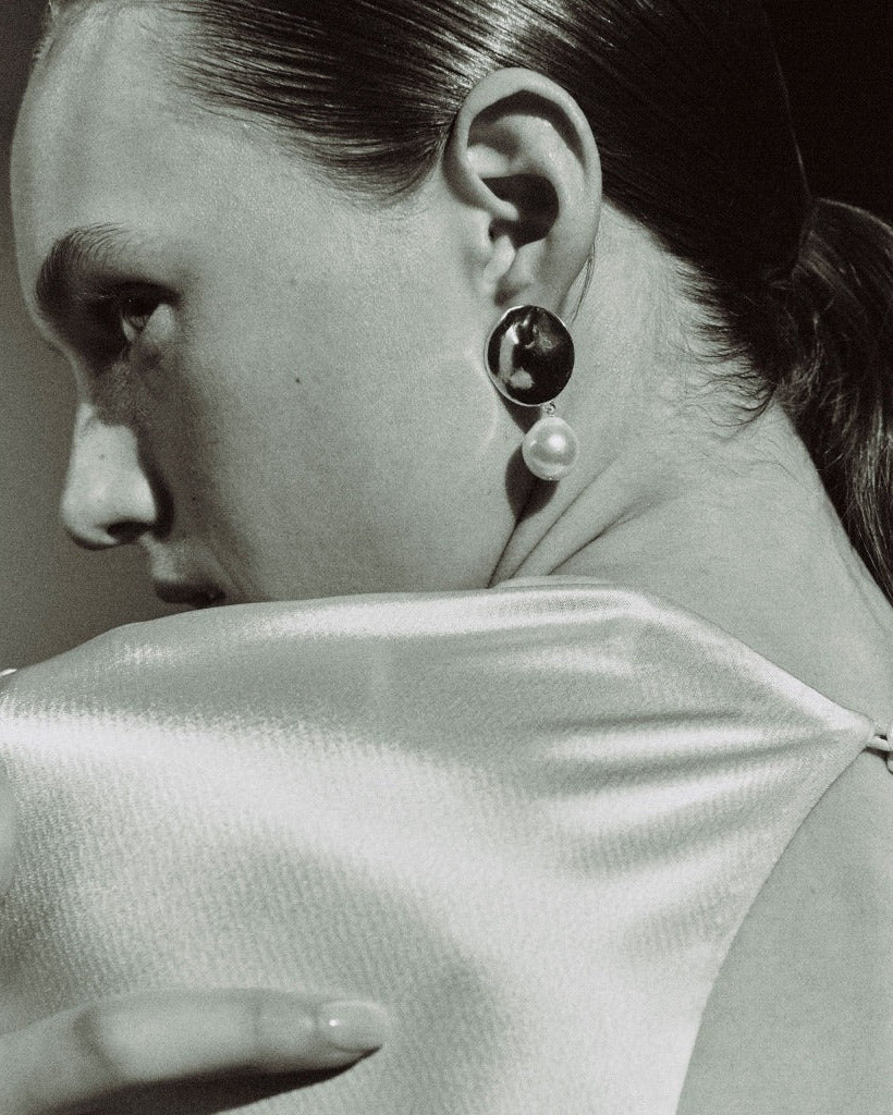 Woman wearing AGMES 0.925 sterling silver disc earrings with freshwater pearl drop.