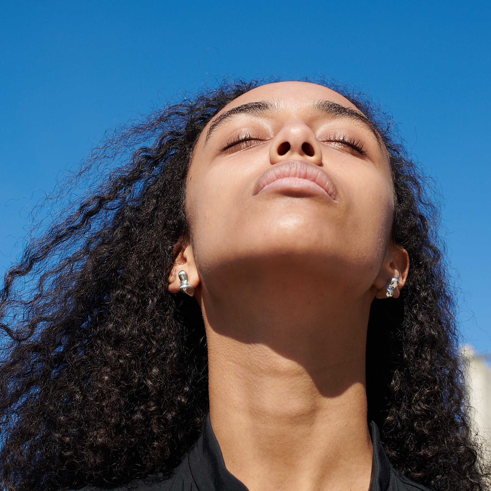 Woman wearing AGMES 0.925 sterling silver sculpted small bubble hoop earrings. Simone Bodmer-Turner.