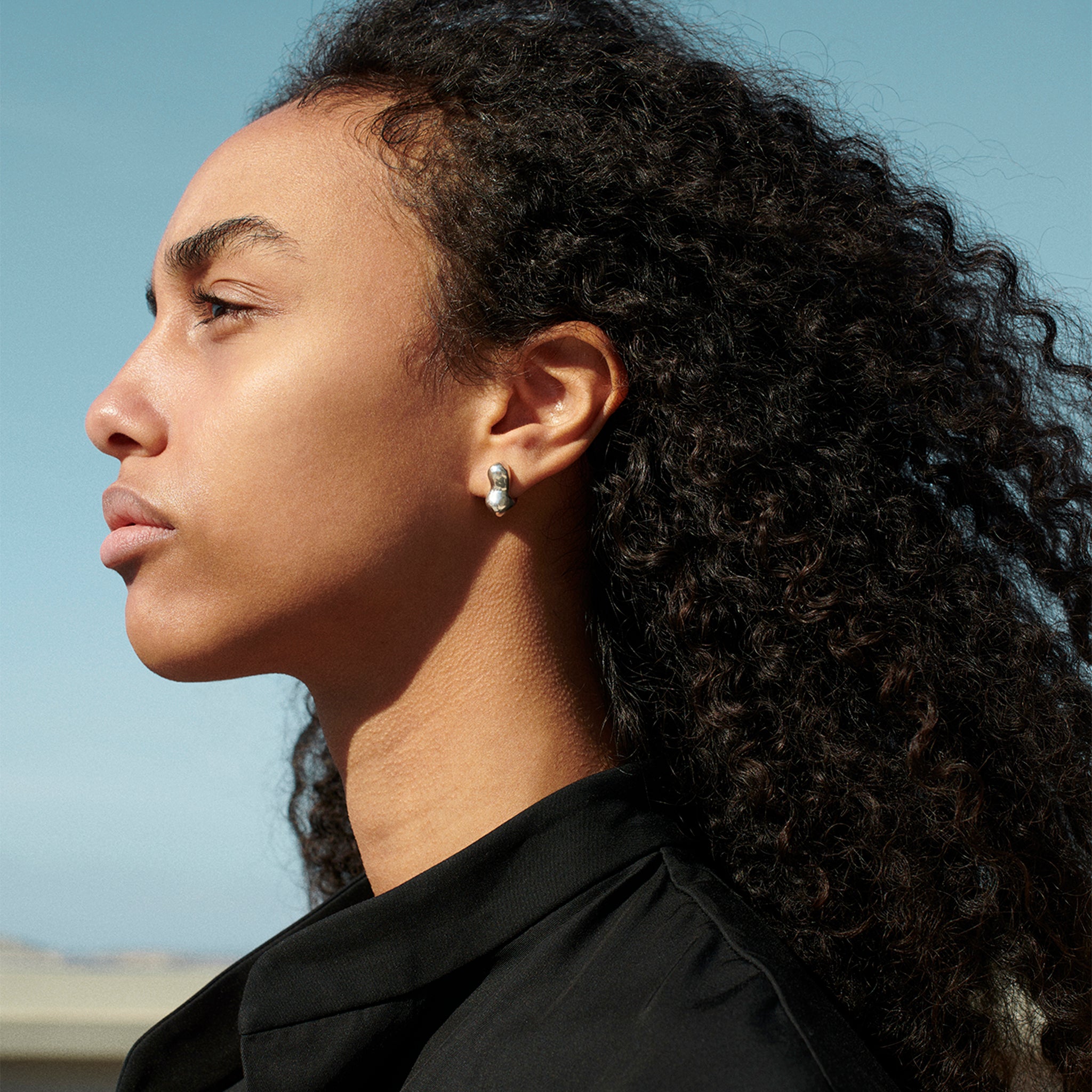Woman wearing AGMES 0.925 sterling silver sculpted small bubble hoop earrings. Simone Bodmer-Turner.
