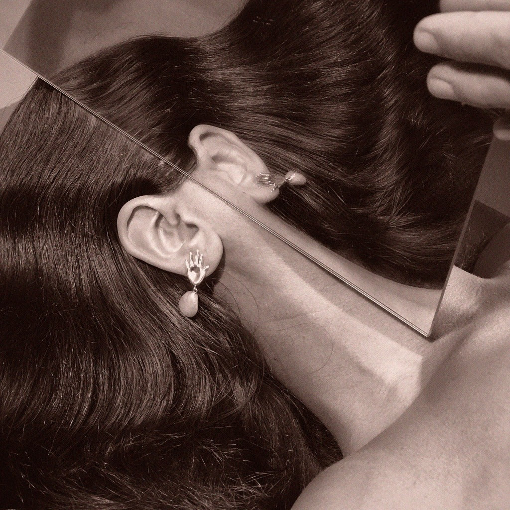 Woman wearing AGMES 0.925 sterling silver abstract hand earrings with baroque freshwater pearl drop.