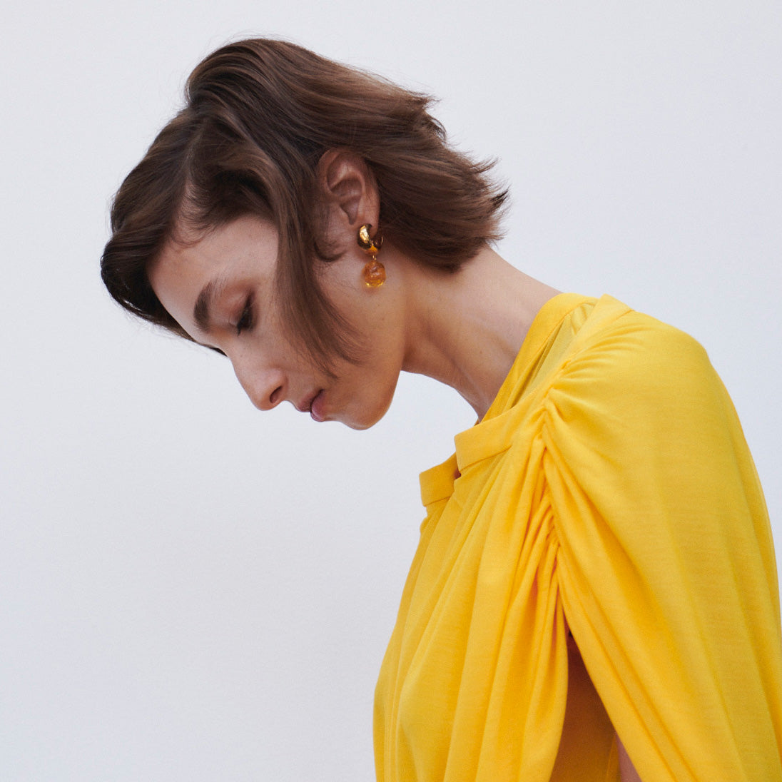 Woman wearing AGMES yellow gold vermeil small Cleo hoop earrings with yellow glass bead drop.