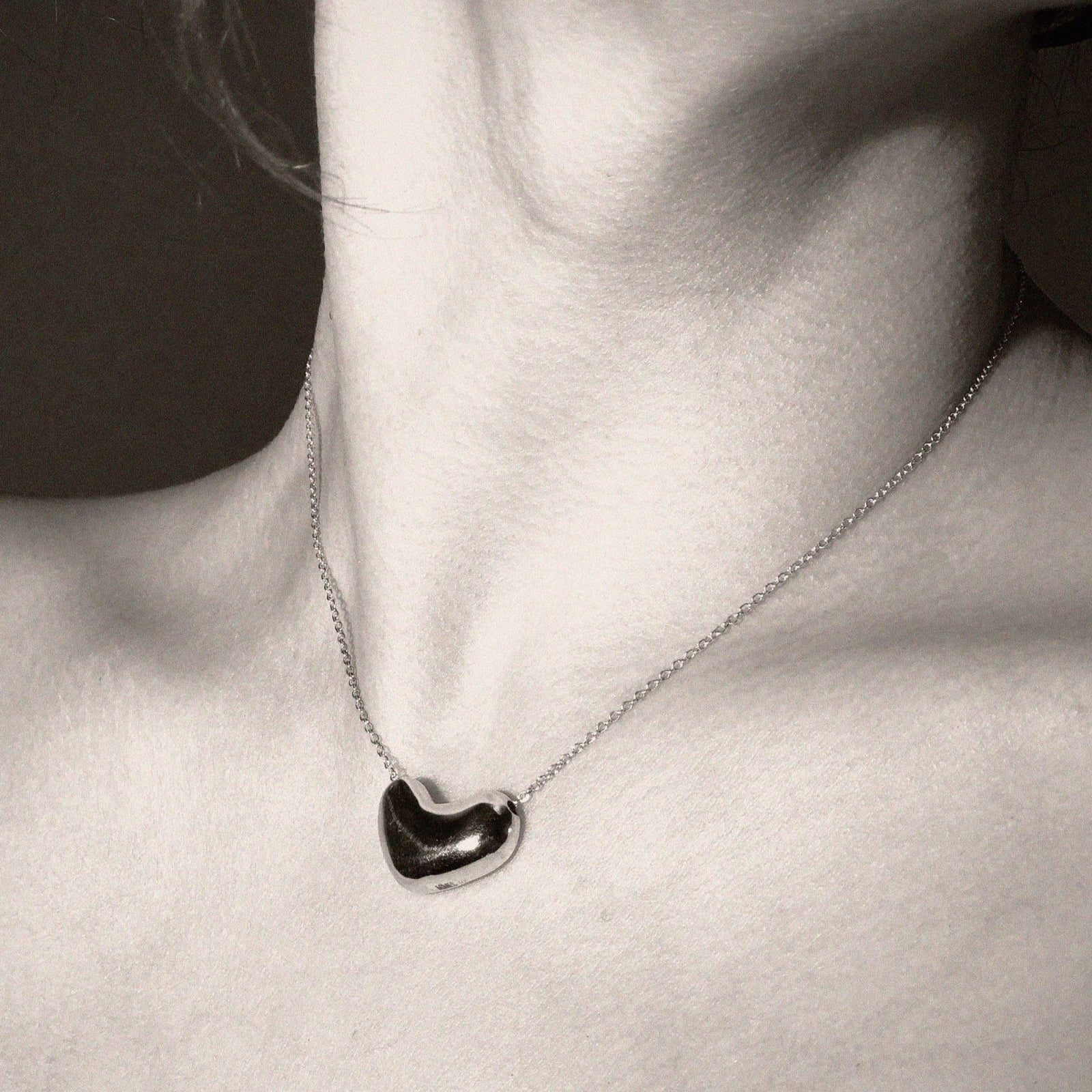 Model wearing AGMES .925 sterling silver Small Sculpted Heart Pendant Necklace. Black and white image.