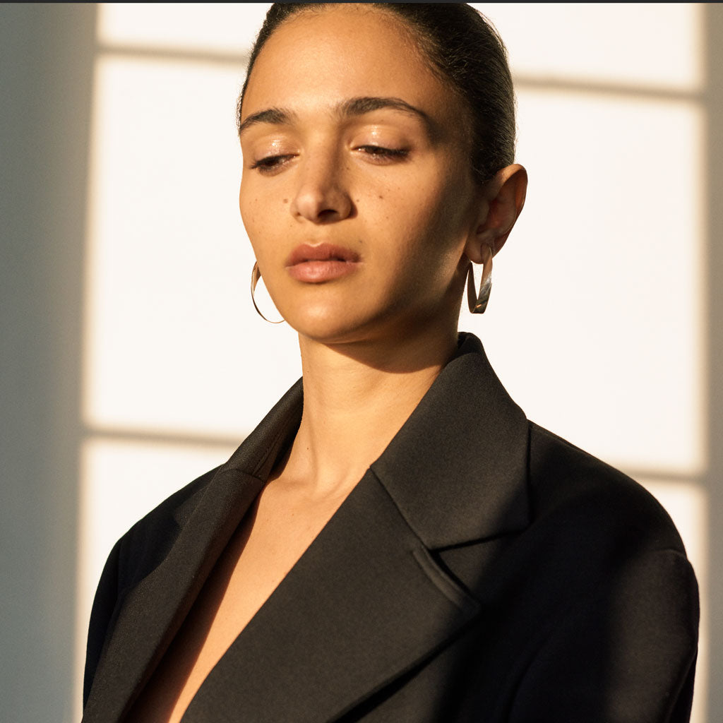 Woman wearing AGMES 18k gold vermeil twist hoop earrings.