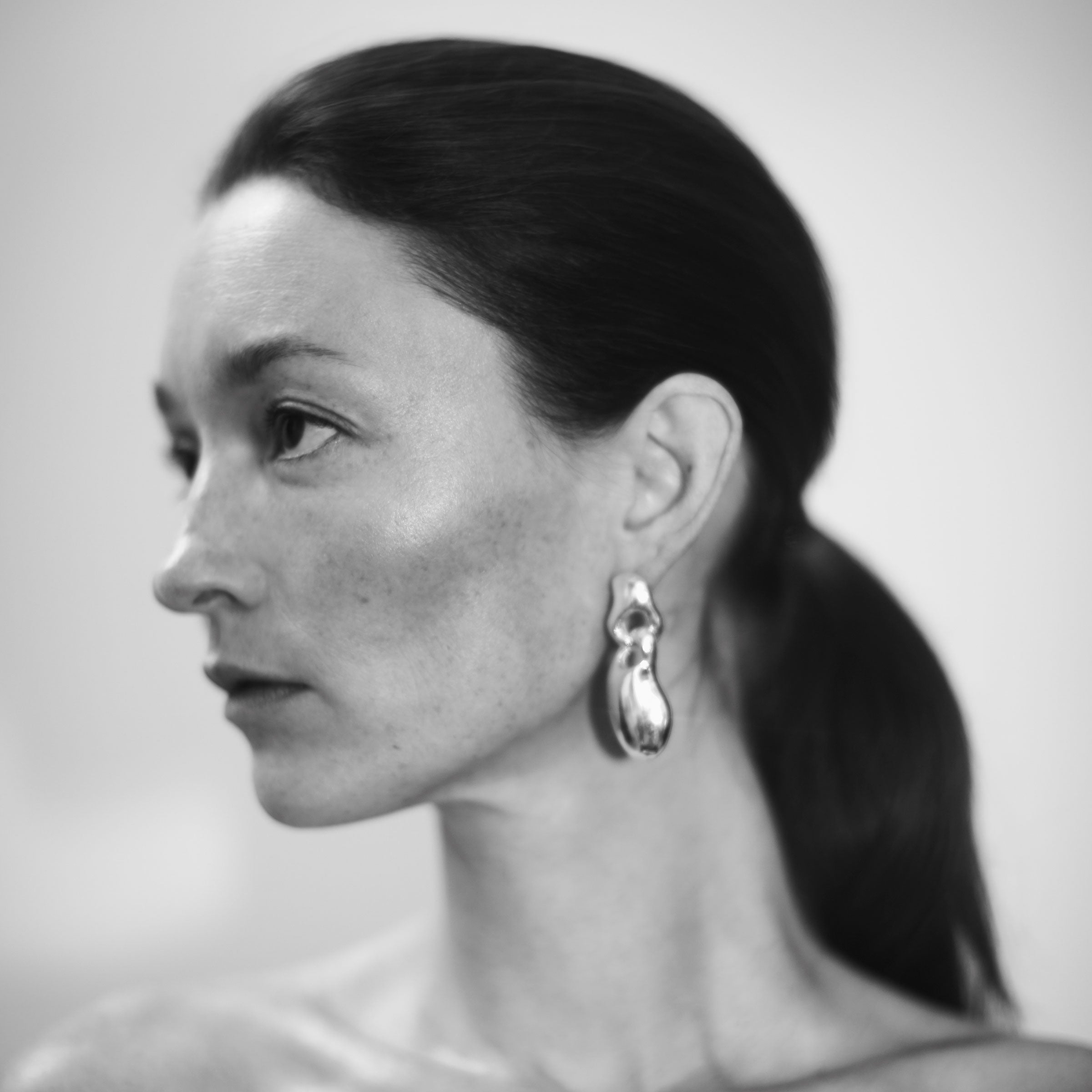 Woman wearing AGMES 0.925 sterling silver sculpted drop earrings.