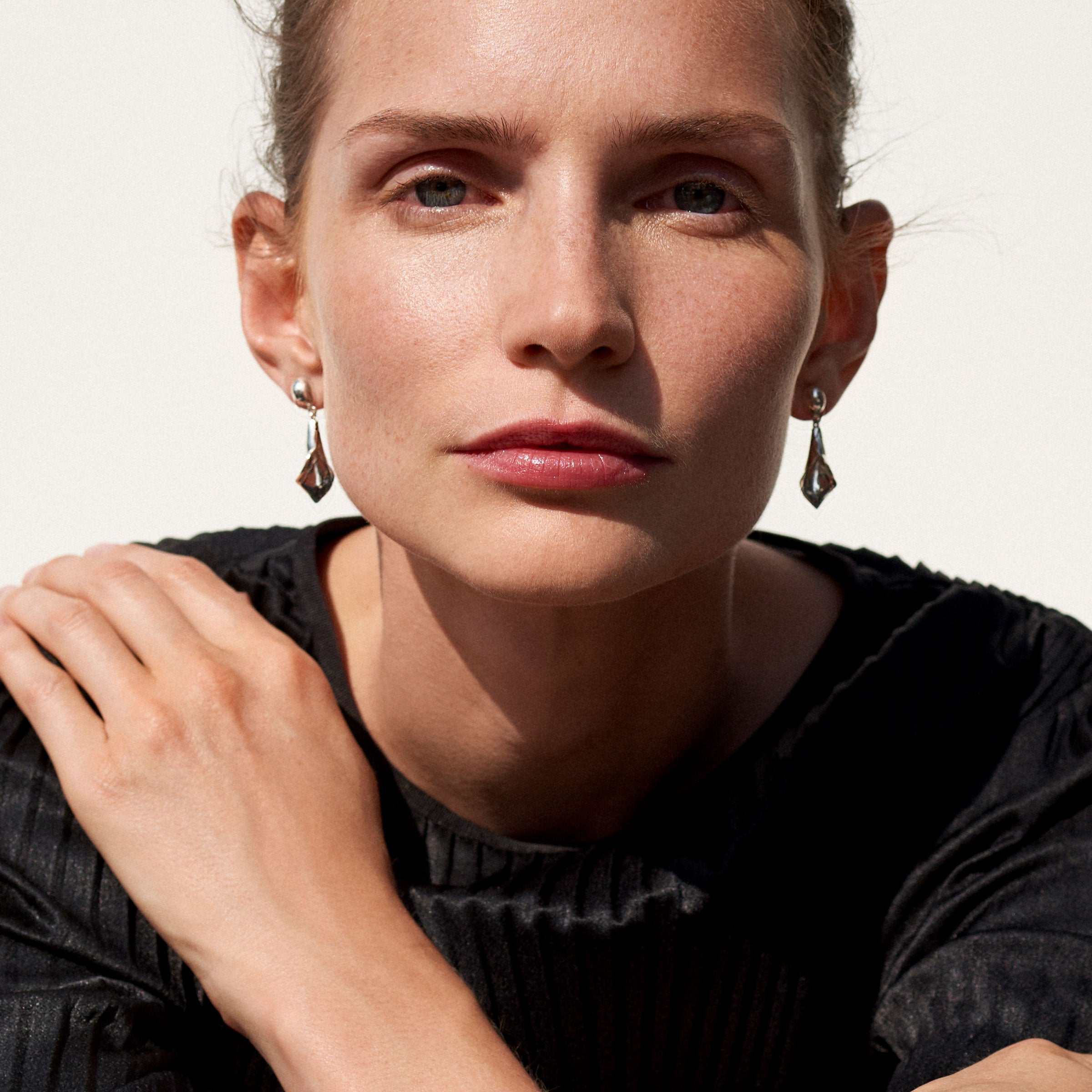 Woman wearing AGMES 0.925 sterling silver mini calla lily inspired drop earrings.