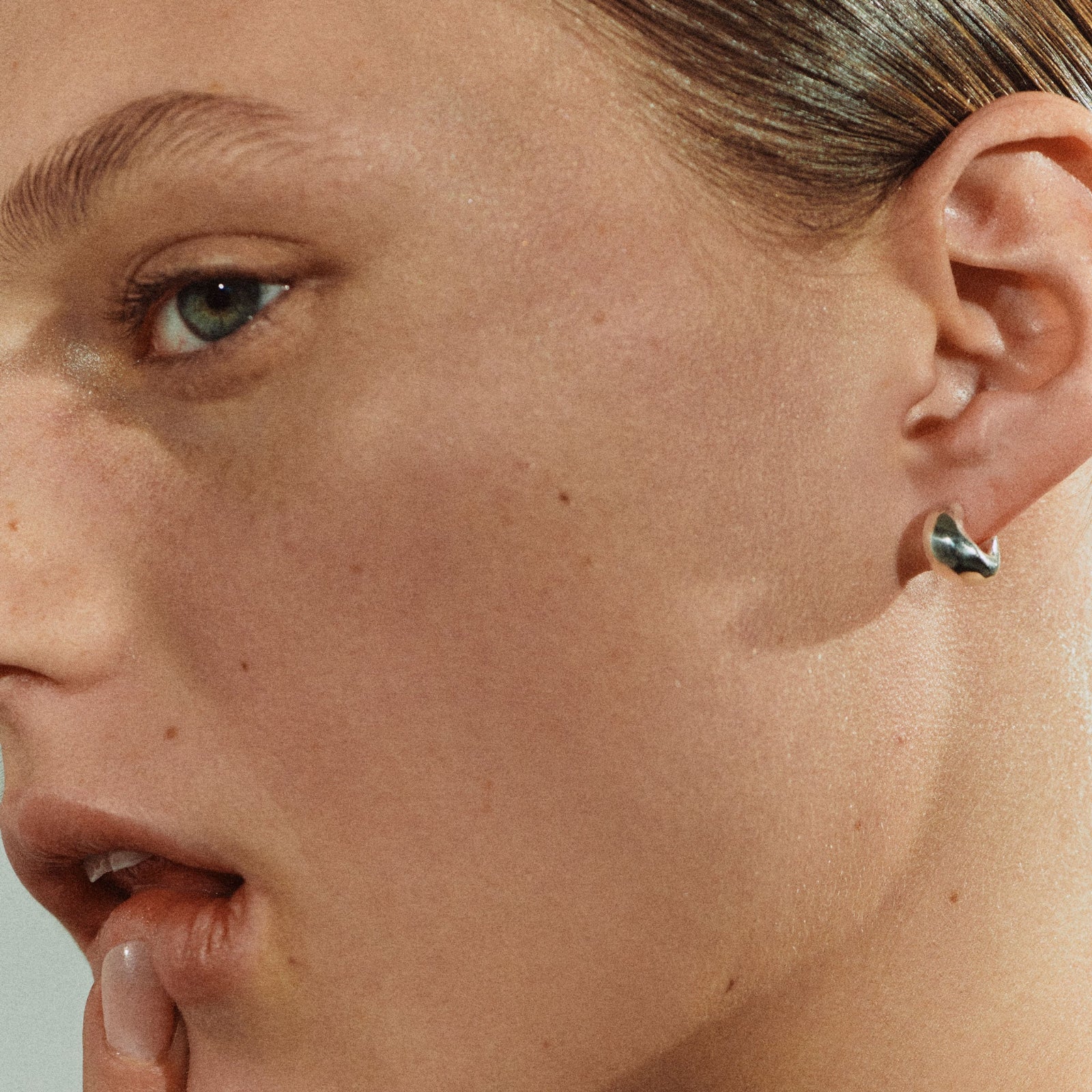 Woman wearing AGMES 0.925 sterling silver thick hoop huggie earrings.