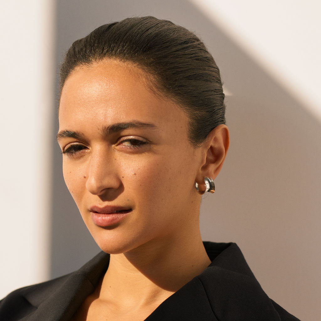 Woman wearing AGMES 0.925 sterling silver mini twist hoop earrings.