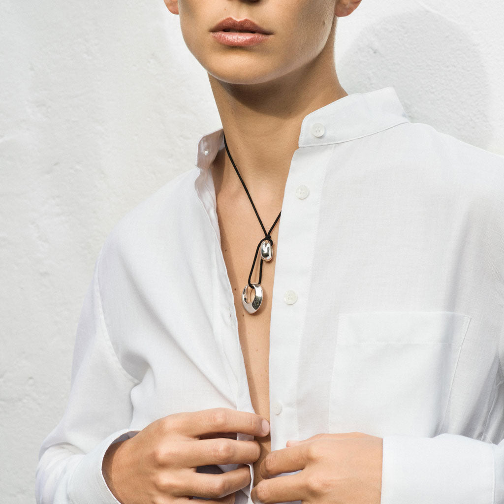 Person wearing AGMES .925 Sterling Silver Rae Pendant with Black Suede Cord necklace under white button down shirt.