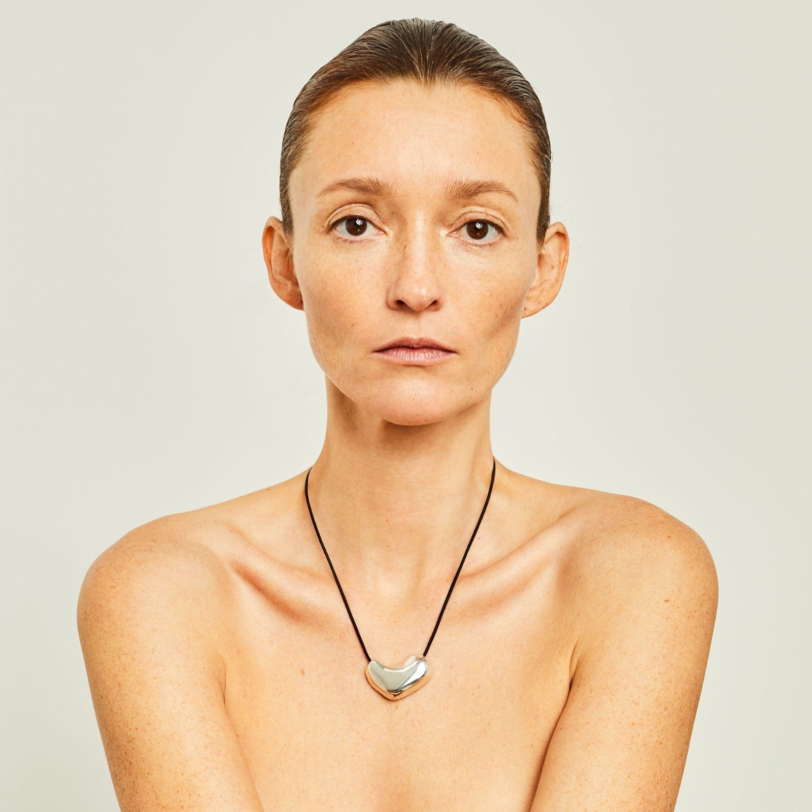 Woman wearing AGMES .925 Sterling Silver Sculpted Heart Pendant on Black Suede Cord.
