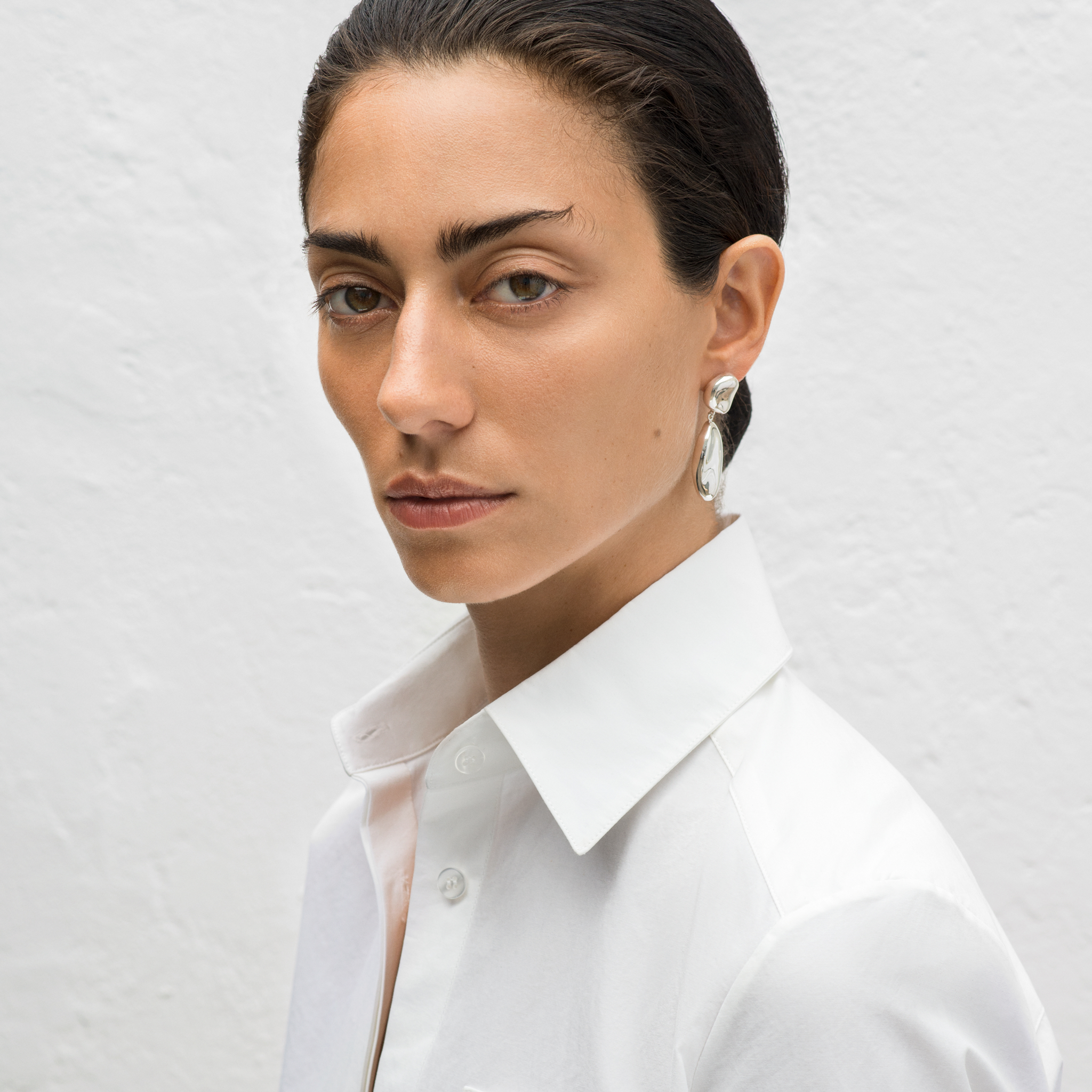 Woman wearing AGMES 0.925 sterling silver sculpted drop earrings.