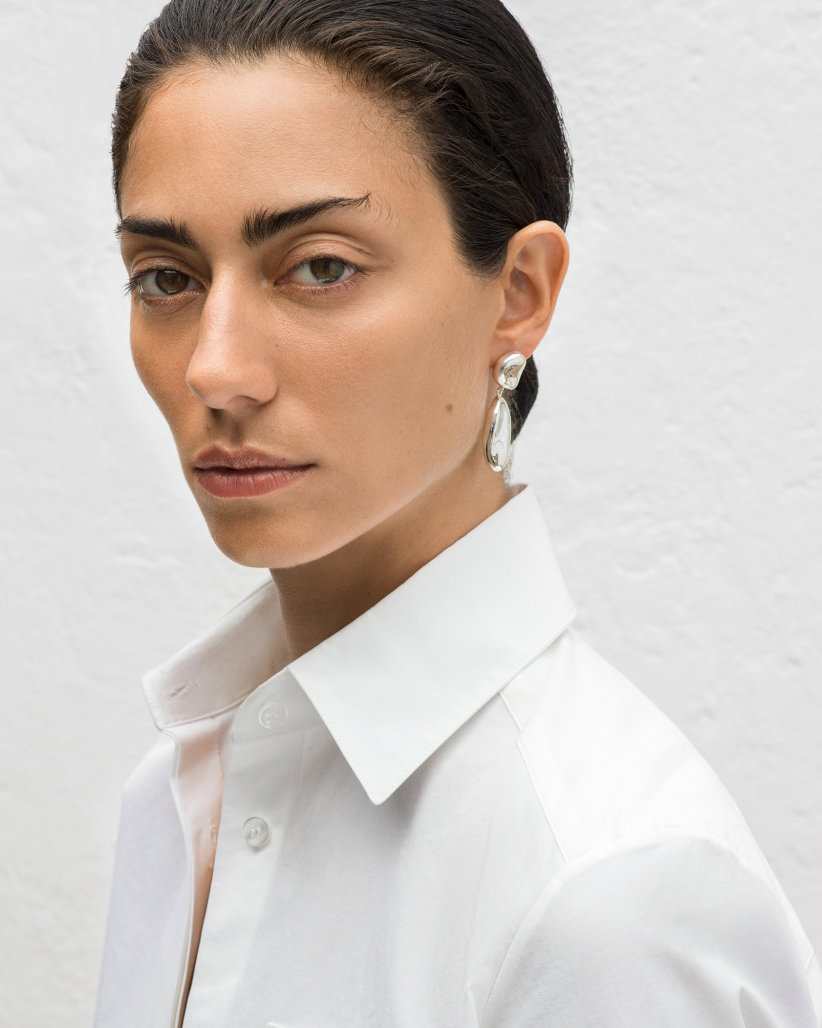 Woman wearing AGMES 0.925 sterling silver sculpted drop earrings.
