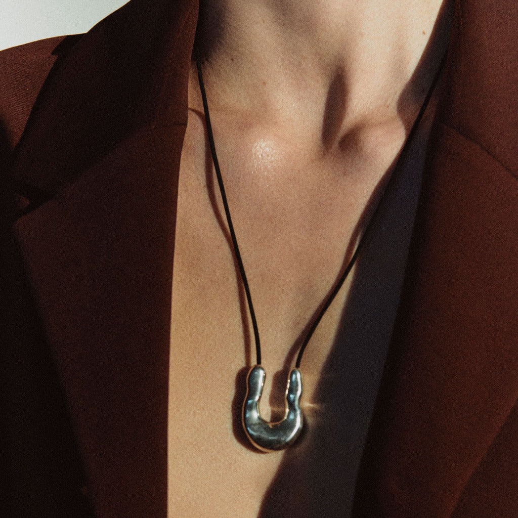 Person wearing AGMES 0.925 sterling silver wishbone pendant on Black Suede cord.