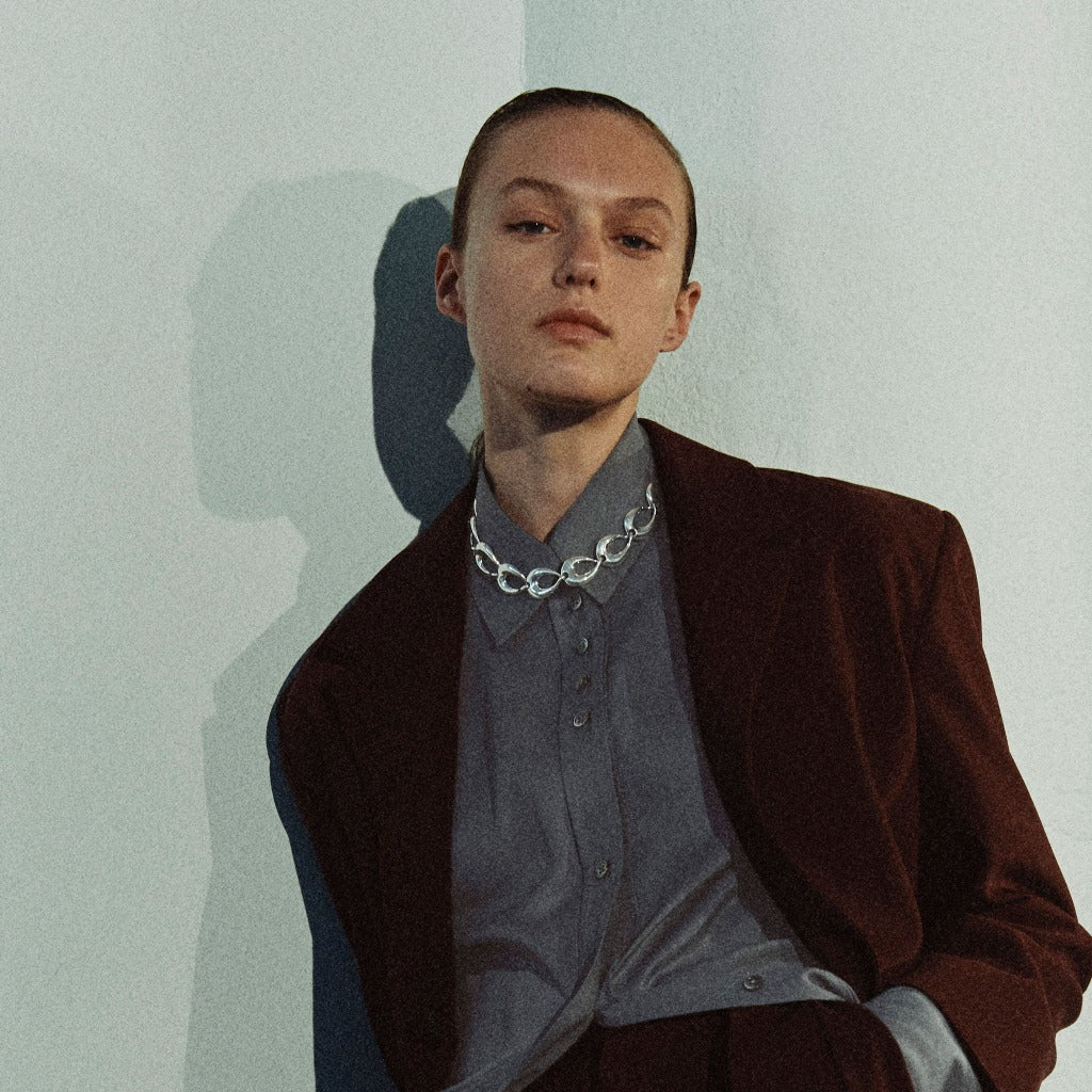 Model wearing AGMES .925 sterling silver sculptural link Tilda Necklace with brown blazer.