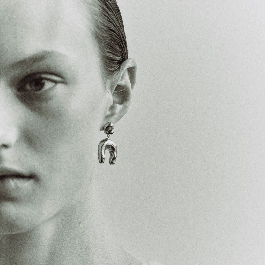 Woman wearing AGMES 0.925 sterling silver earrings with sculpted wishbone drop.