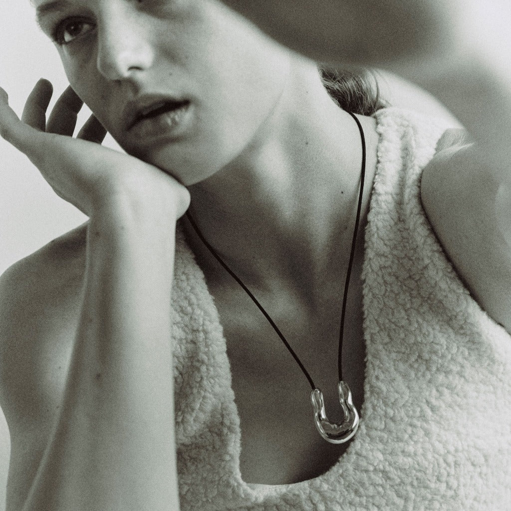 Woman wearing AGMES 0.925 sterling silver wishbone pendant on black suede cord.