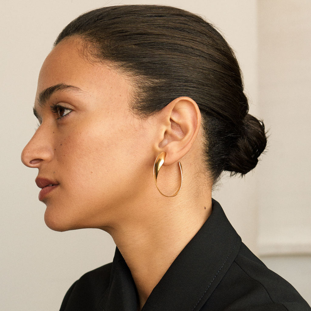Woman wearing AGMES 18k gold vermeil twist hoop earrings.