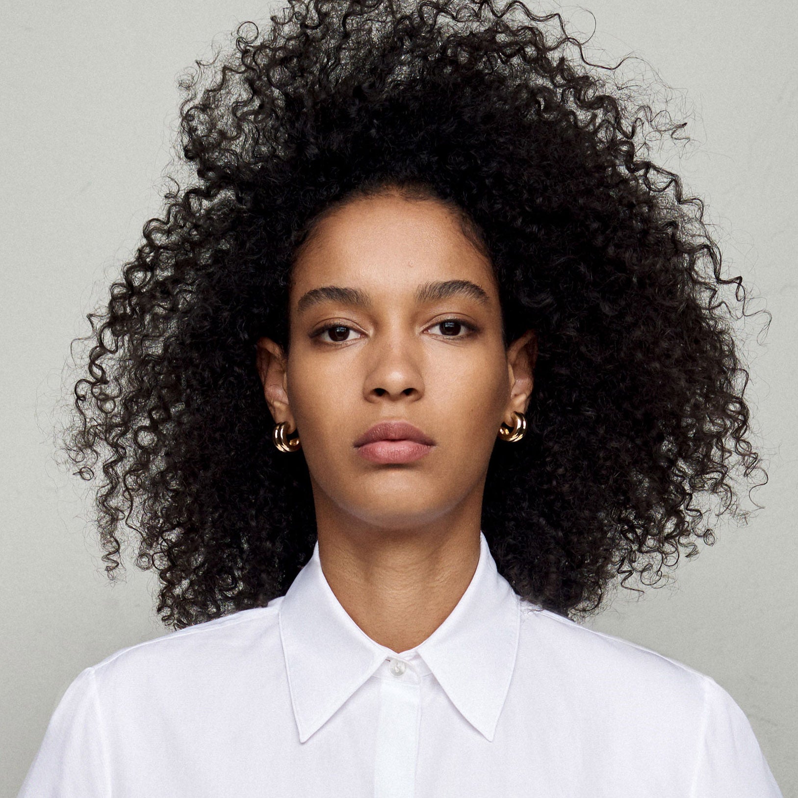 Woman wearing AGMES 18k gold vermeil double ridged small hoop earrings.