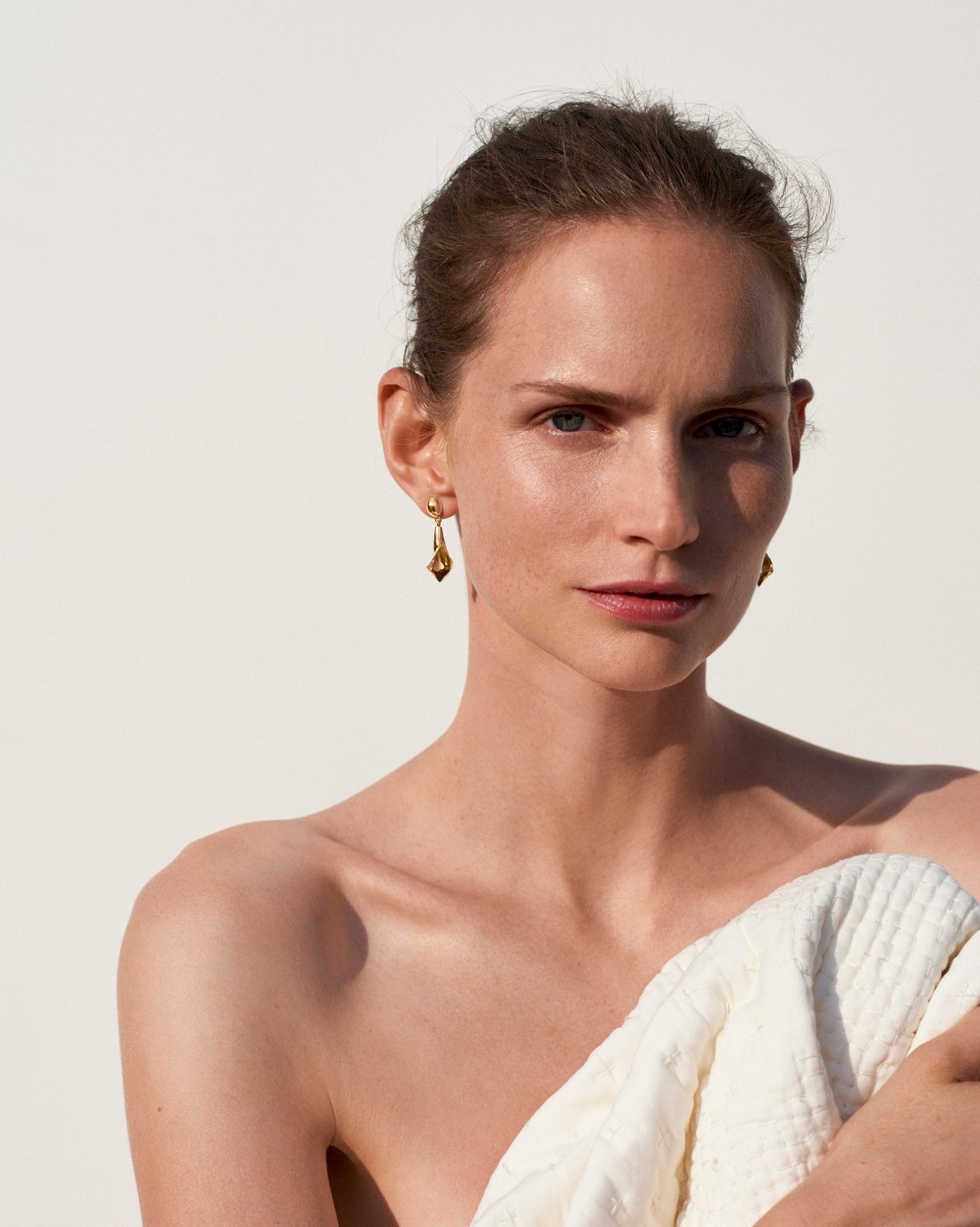 Woman wearing AGMES 18k gold vermeil mini calla lily inspired drop earrings.