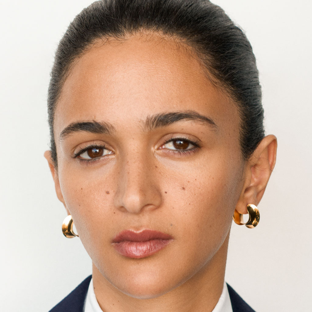 Woman wearing AGMES 18k gold vermeil mini twist hoop earrings.