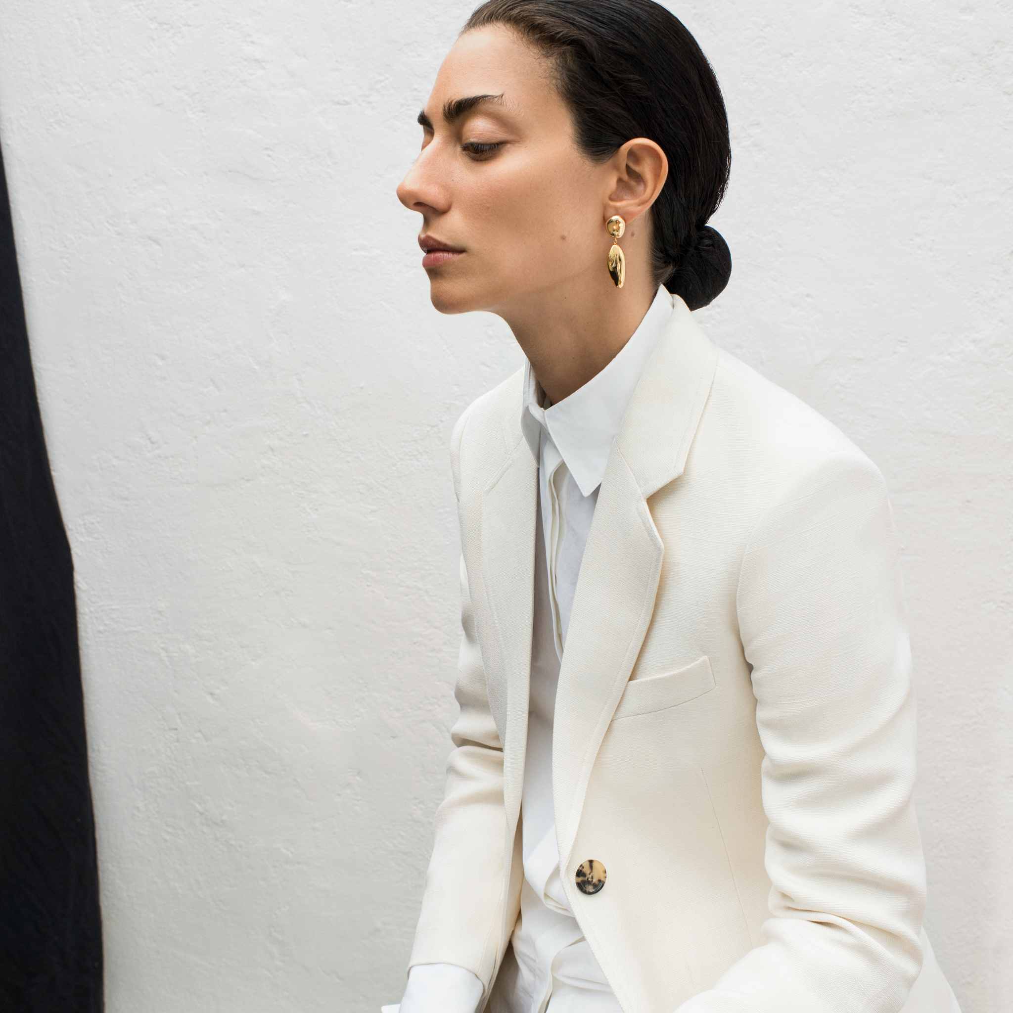 Woman wearing AGMES 18k gold vermeil sculpted drop earrings.