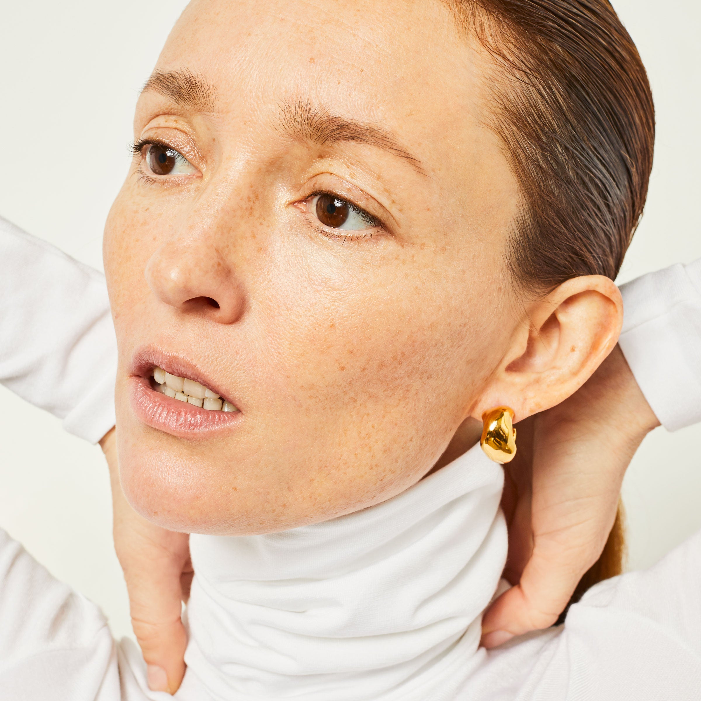 Person wearing AGMES 18k gold vermeil small hoop earrings.