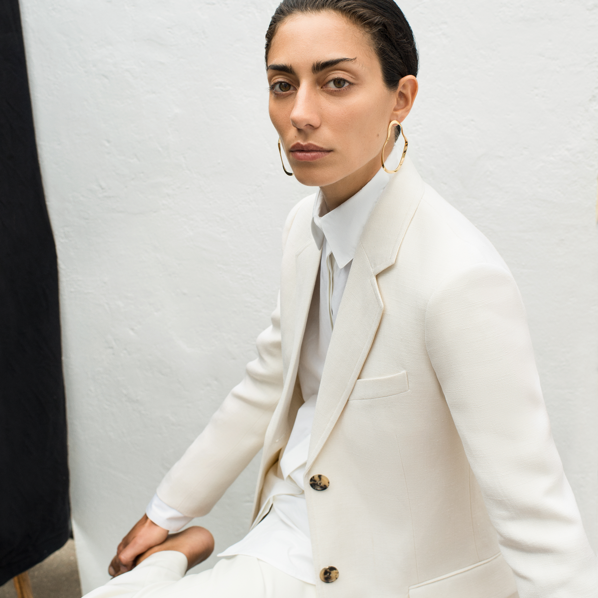 Woman wearing AGMES 18k gold vermeil sculptural wavy round hoop earrings.