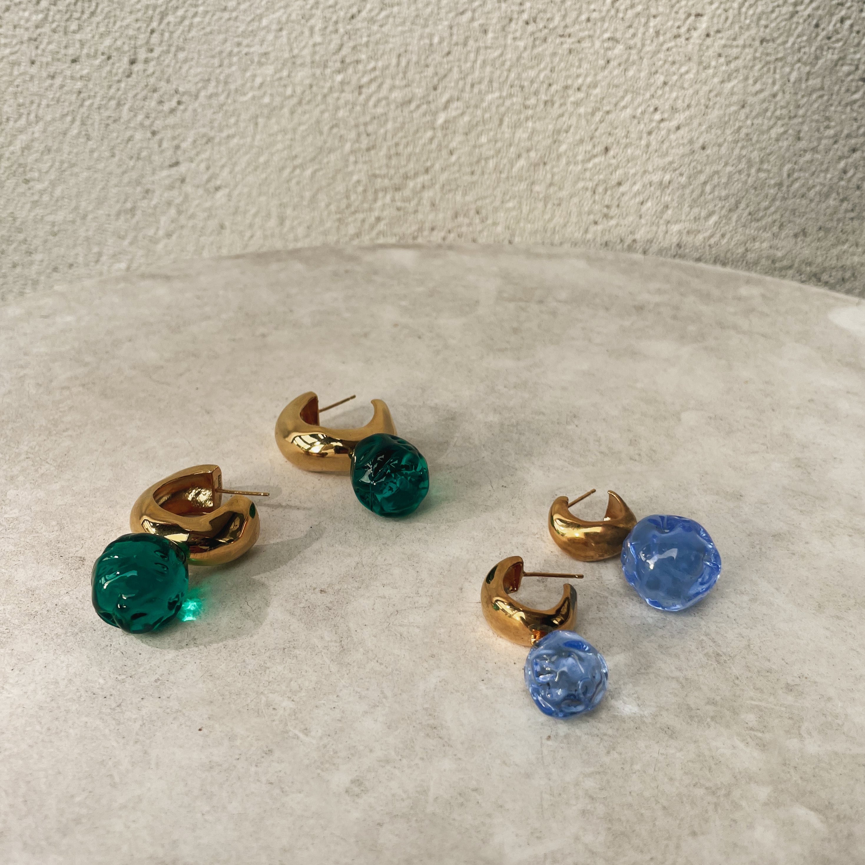 AGMES yellow gold vermeil medium Cleo hoop earrings with green and blue glass bead drop on natural stone background.