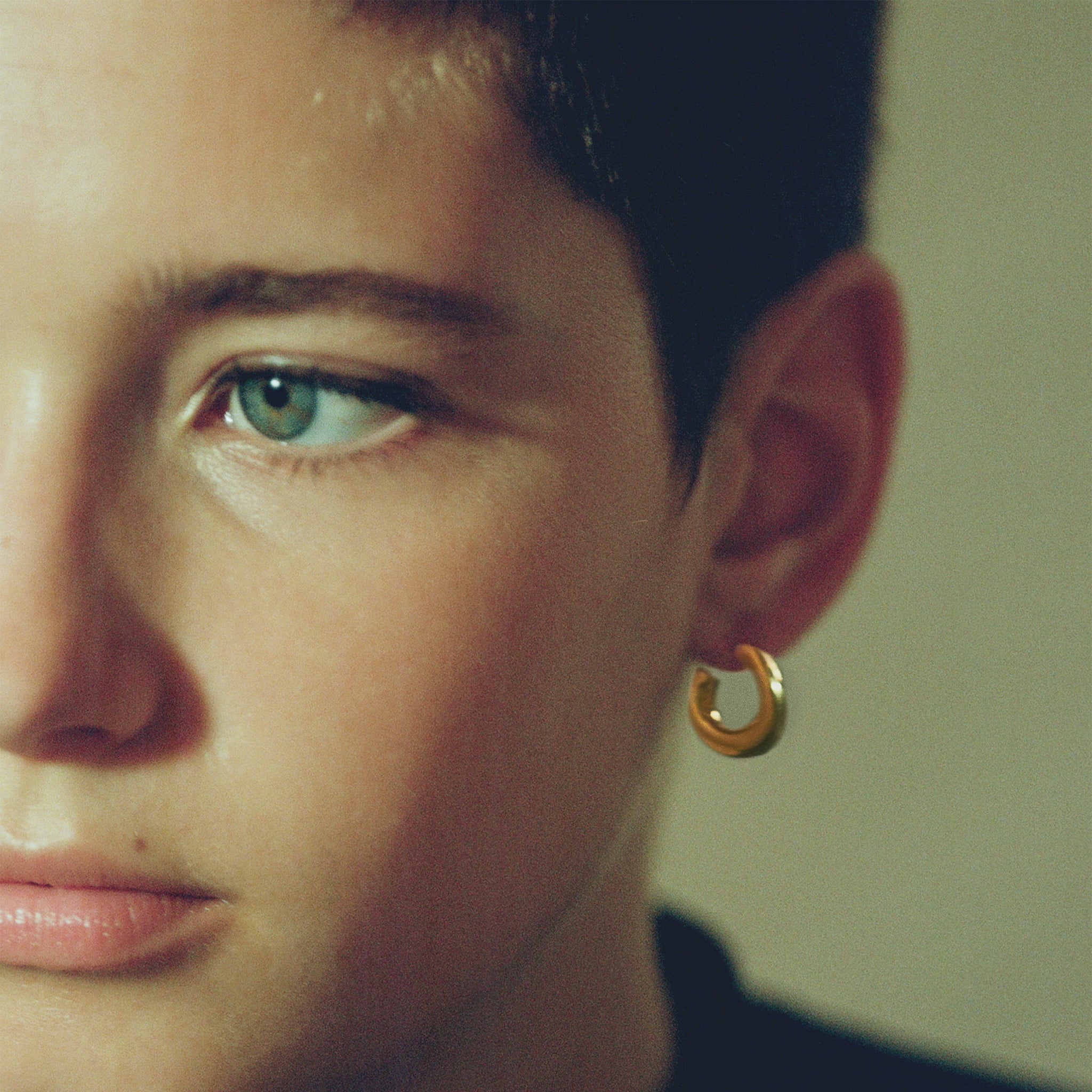 Person wearing AGMES 18k gold vermeil mini hoop earrings.