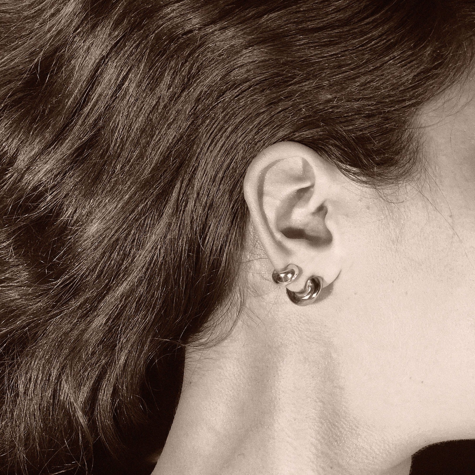 Woman wearing AGMES 0.925 sterling silver thick hoop huggie earrings.