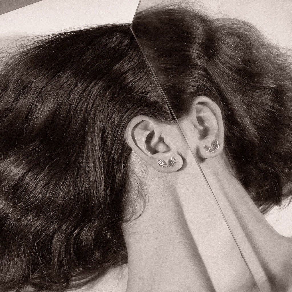 Woman wearing AGMES 0.925 sterling silver small hand shaped stud earrings.